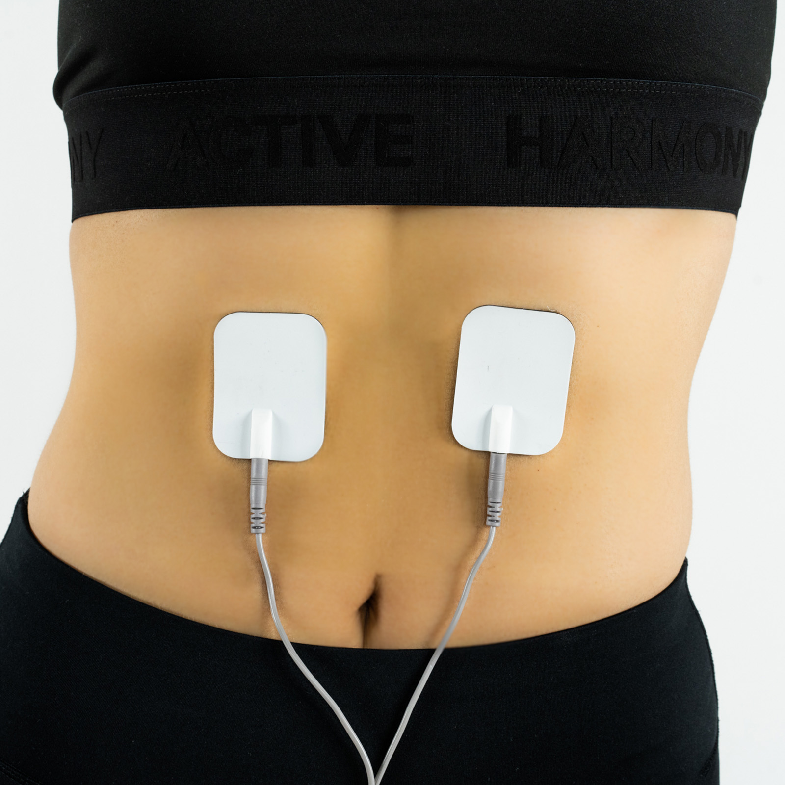 Torso de mujer con dos electrodos blancos conectados a un dispositivo, colocados en su abdomen.