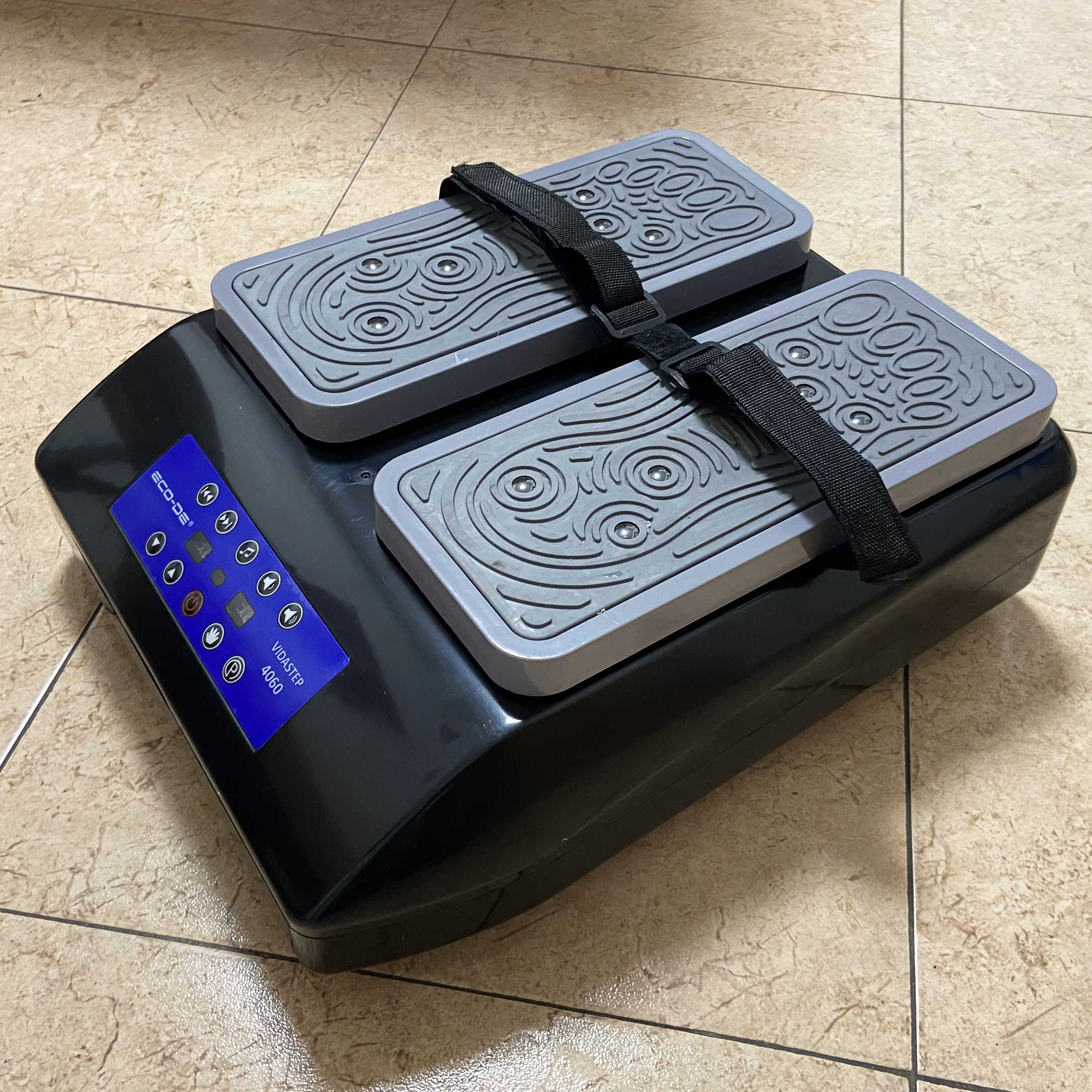Stepper negro con dos plataformas para los pies, una correa negra y una pantalla digital azul.