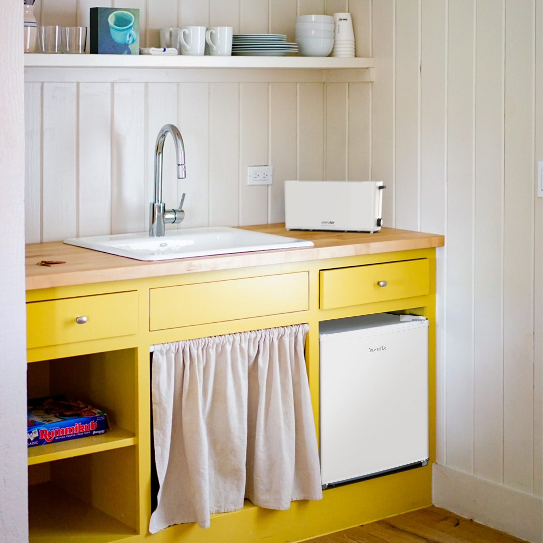Una cocina amarilla con gabinetes, un fregadero y una mini nevera debajo de una encimera.