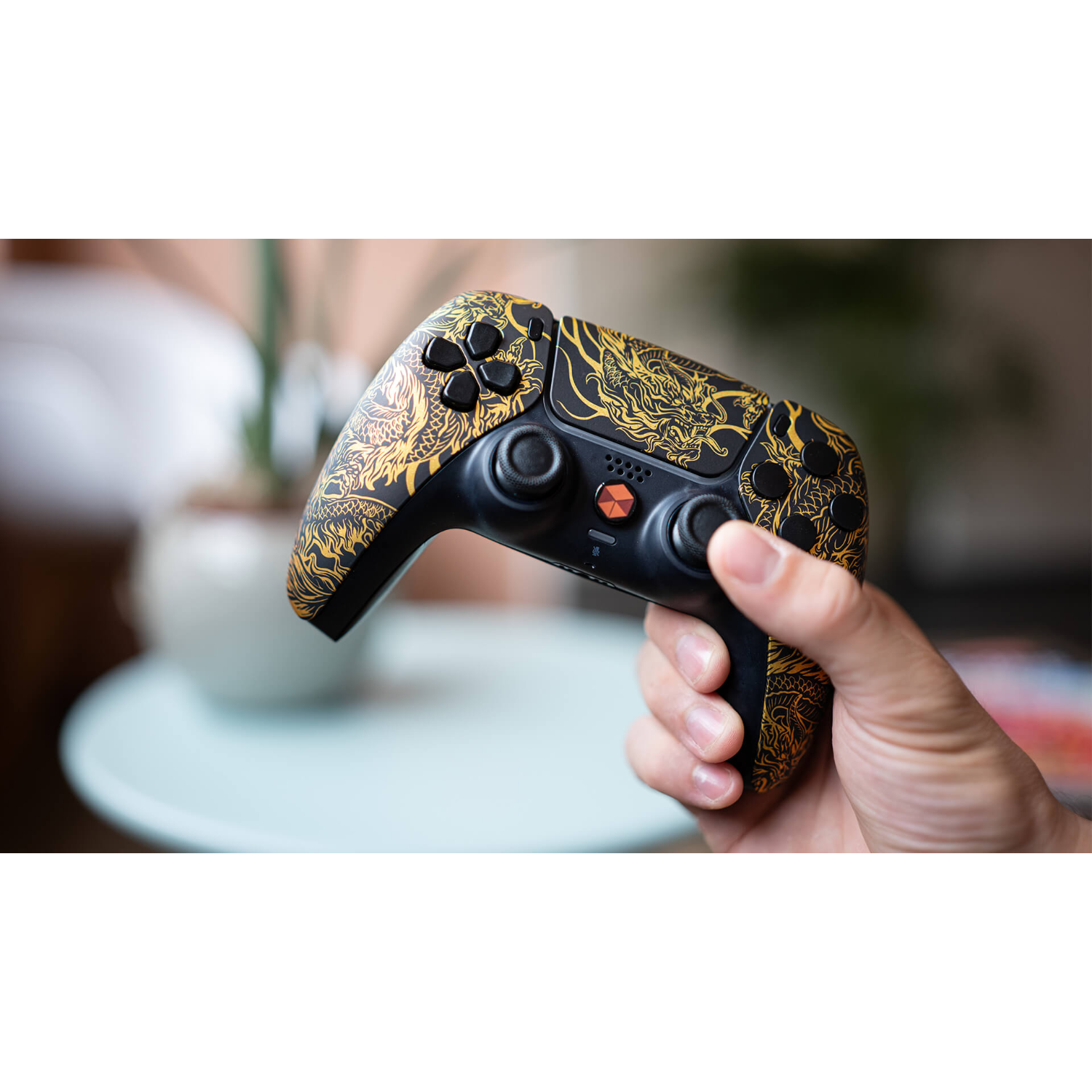 Mano che tiene un controller di gioco nero e oro con design a drago.