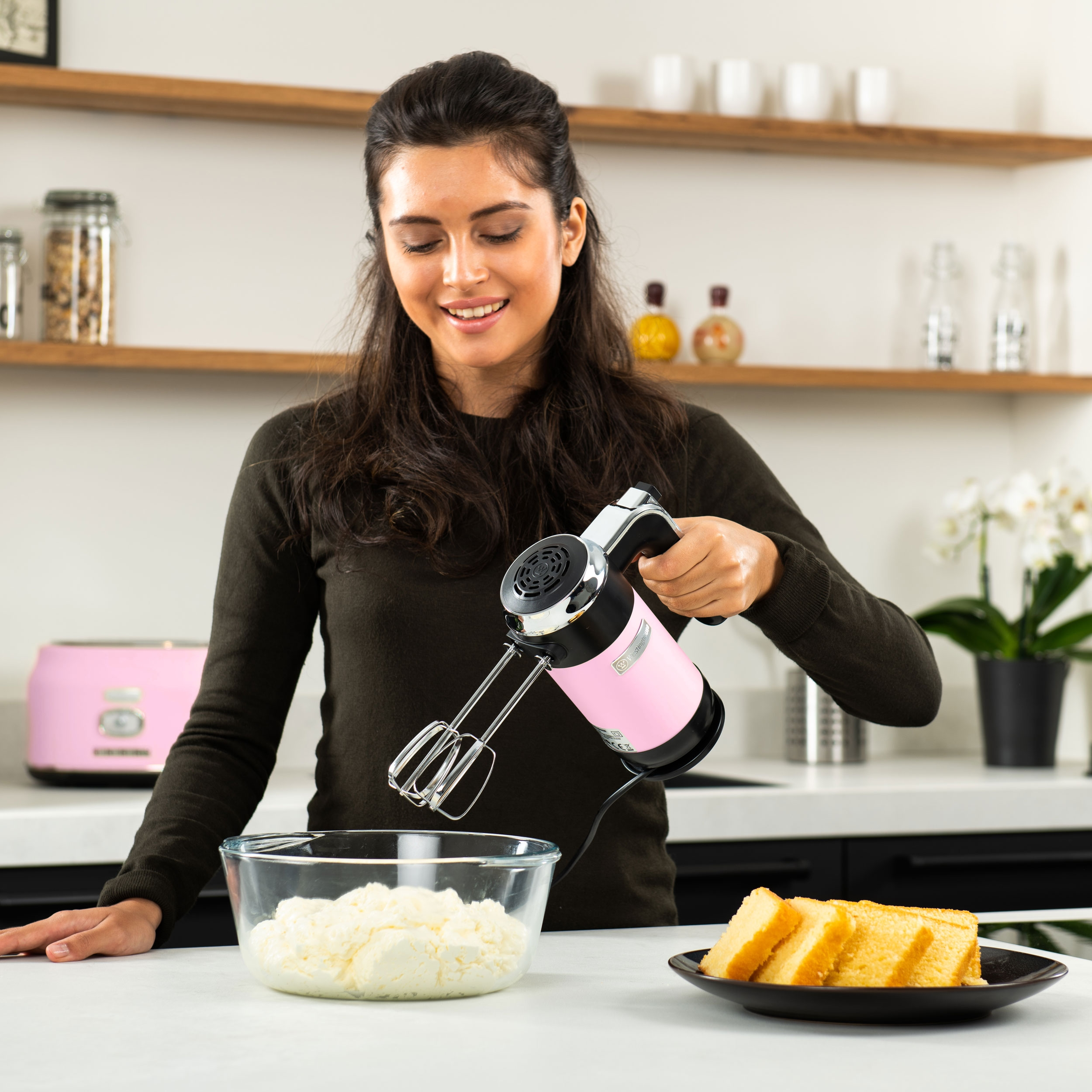 Eine Frau, die einen pinken Handmixer benutzt, um Zutaten in einer Schüssel zu verrühren.