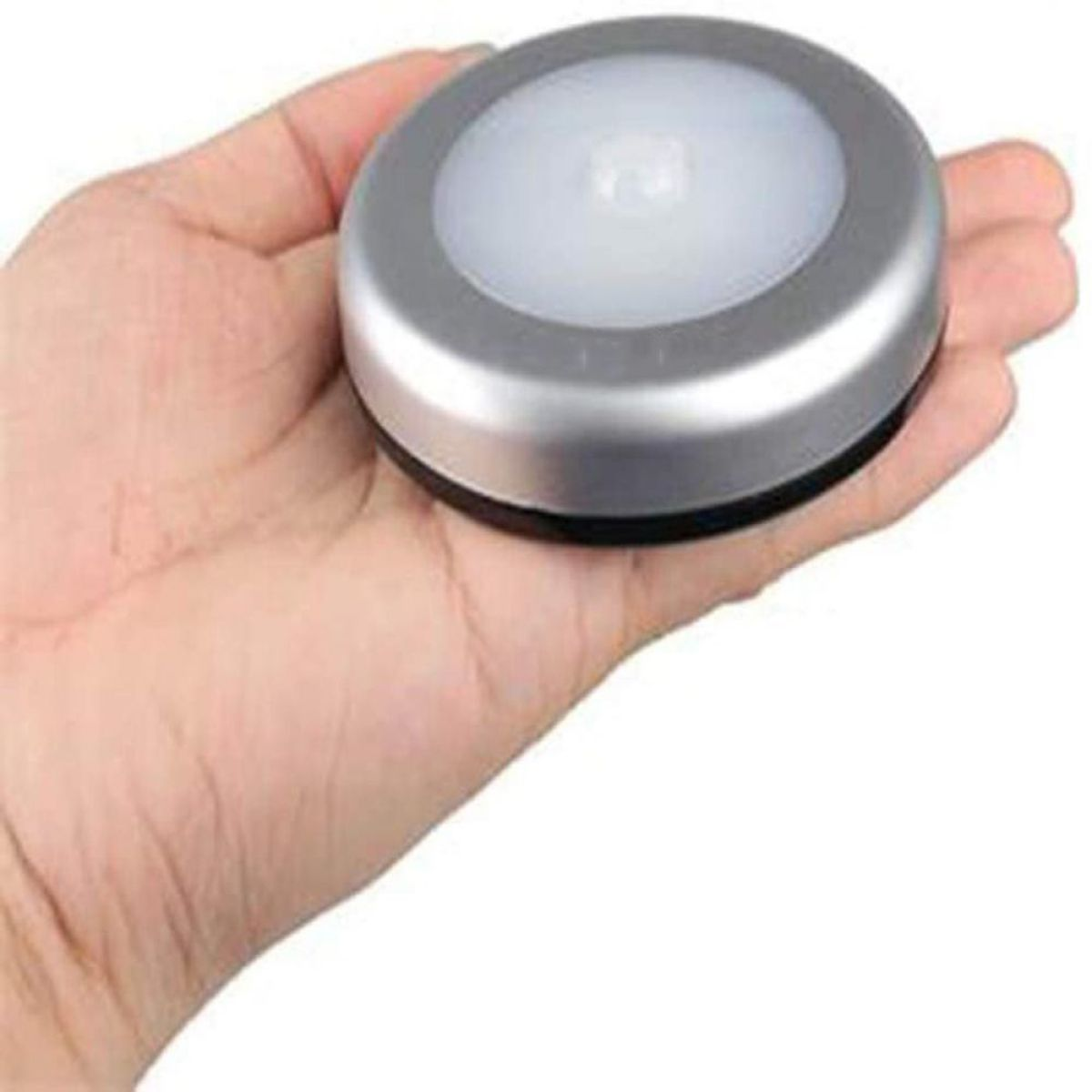 Eine Hand, die ein silbernes und schwarzes rundes LED-Licht hält.