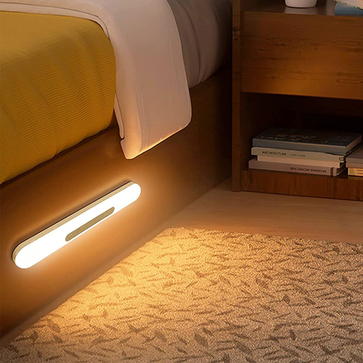 Eine an der Wand montierte LED-Leuchte neben einem Bett, die das Bett und einen Nachttisch beleuchtet.