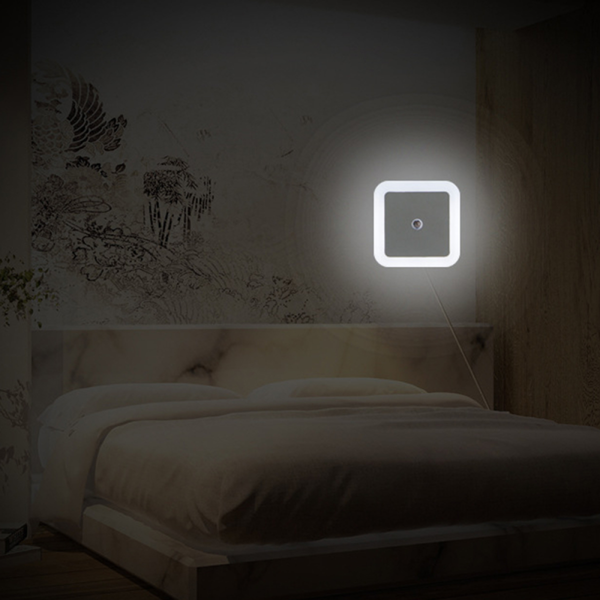 Ein beleuchtetes quadratisches Nachtlicht an einer Wand über einem Bett. Der Raum ist schwach beleuchtet.