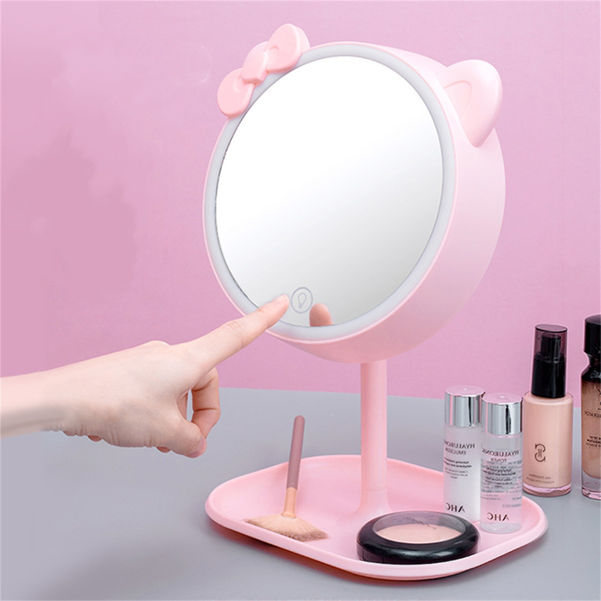 Rosa Hello Kitty Spiegel mit berührungsempfindlicher Taste. Make-up und eine Hand im Bild.