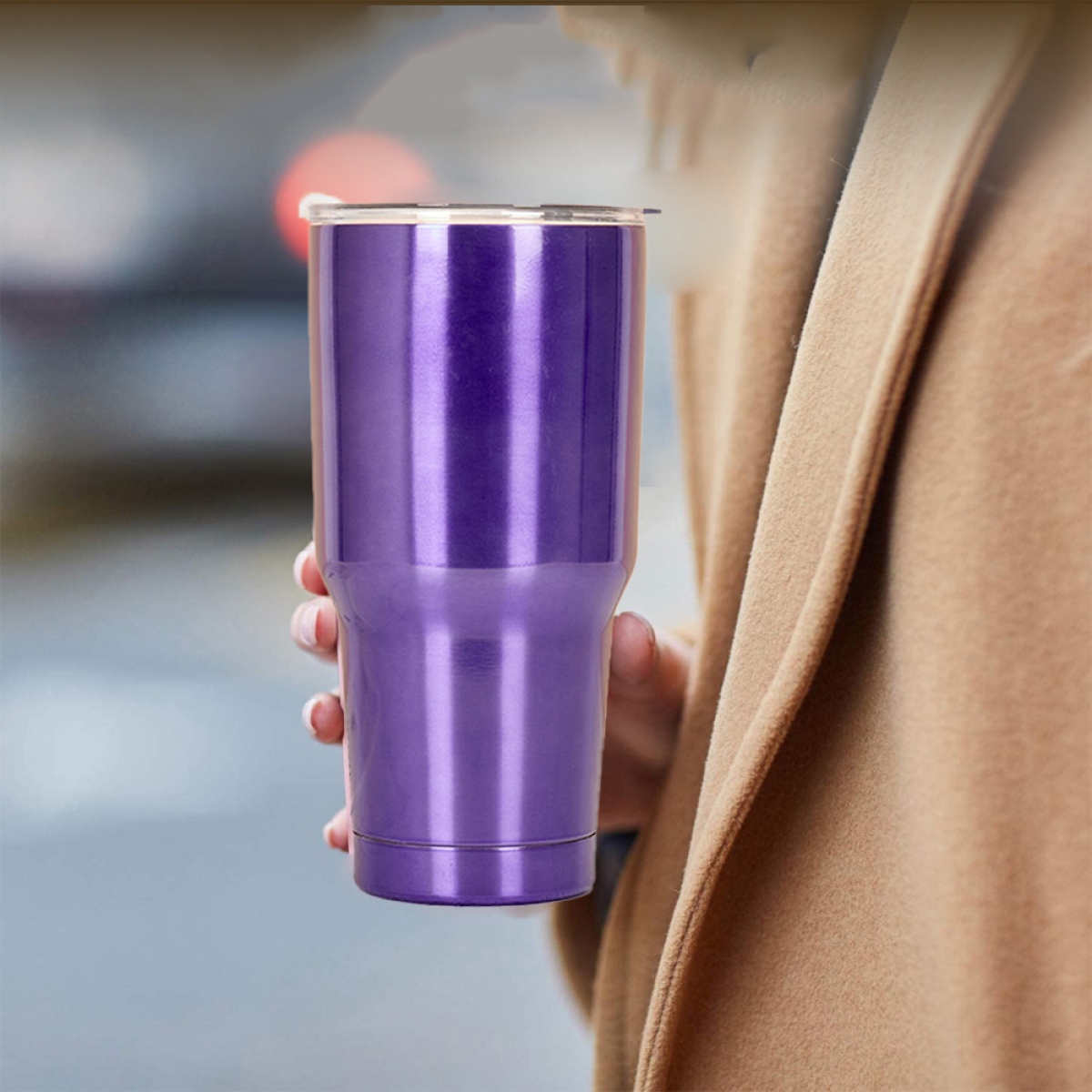 Eine Person hält einen violetten isolierten Becher. Der Hintergrund ist verschwommen.