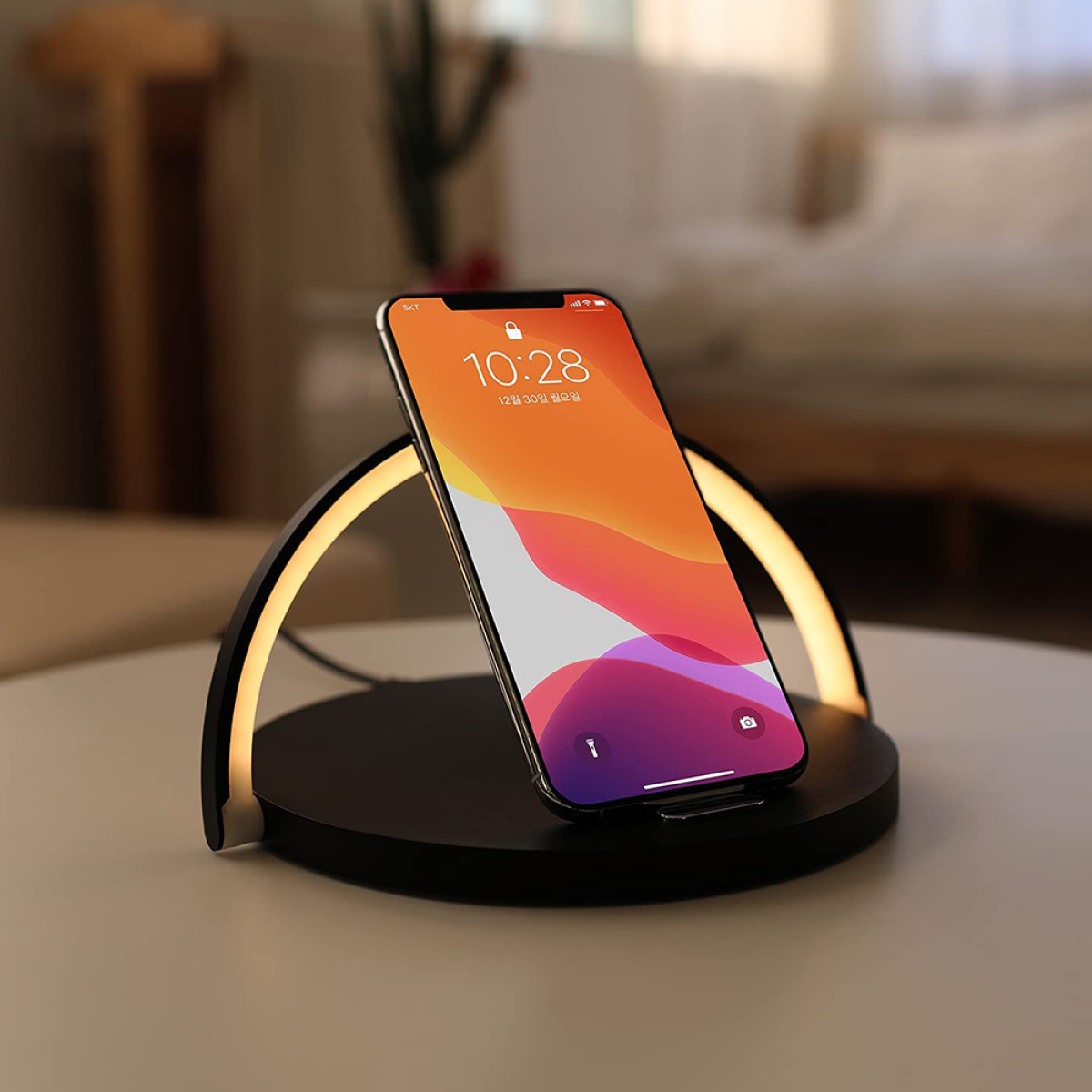 Smartphone auf einem schwarzen kabellosen Ladegerät, mit warmem Licht, auf weißem Tisch.