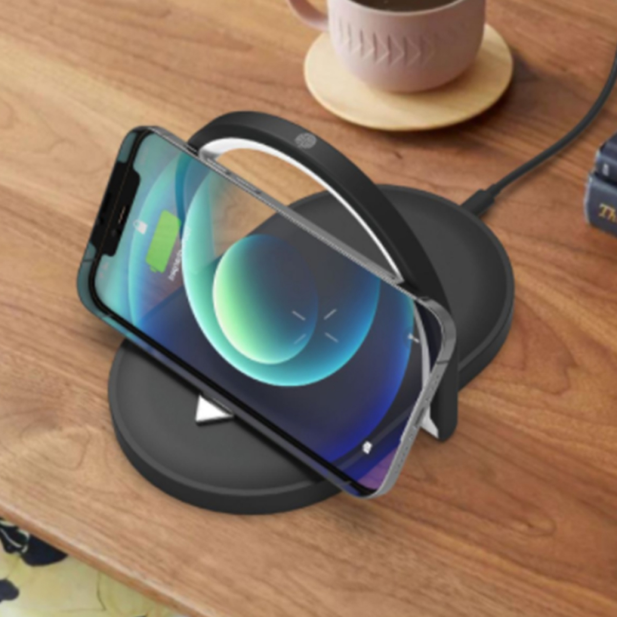 Schwarzes kabelloses Ladepad mit einem Telefon darauf, Holztisch Hintergrund.