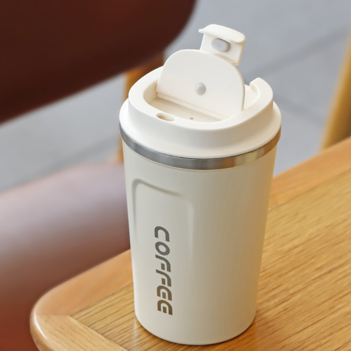 Becher in cremefarben mit weißem Deckel. Das Wort "COFFEE" ist auf dem Becher aufgedruckt.
