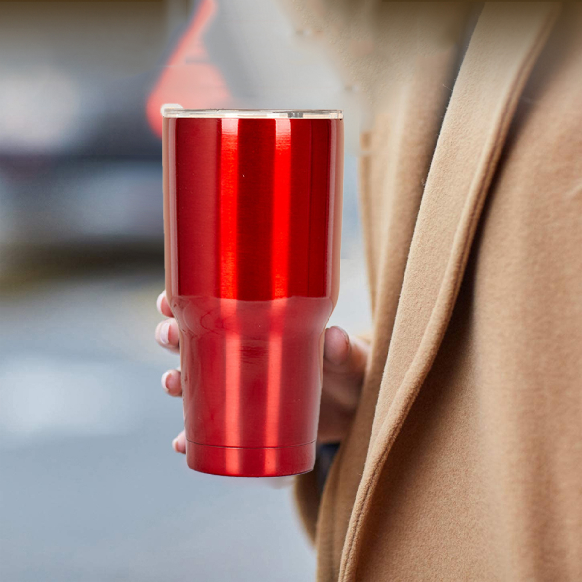 Person hält roten Becher, Nahaufnahme, unscharfer Hintergrund.
