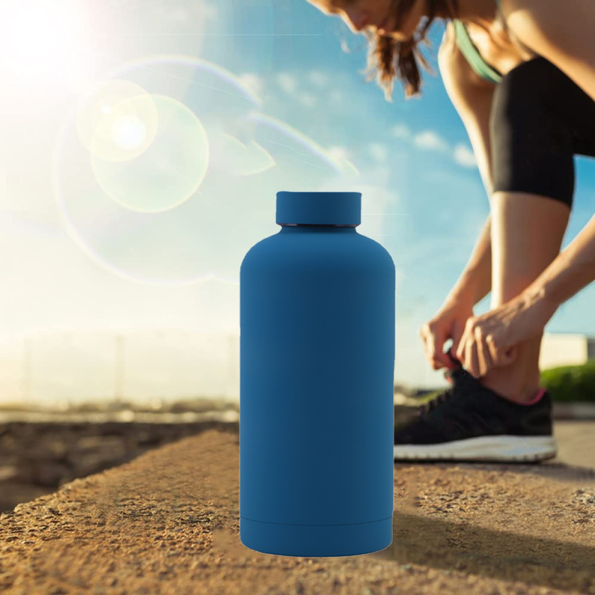 Blaue Wasserflasche, eine Frau, die im Hintergrund ihren Schuh bindet, und Sonnenlicht.