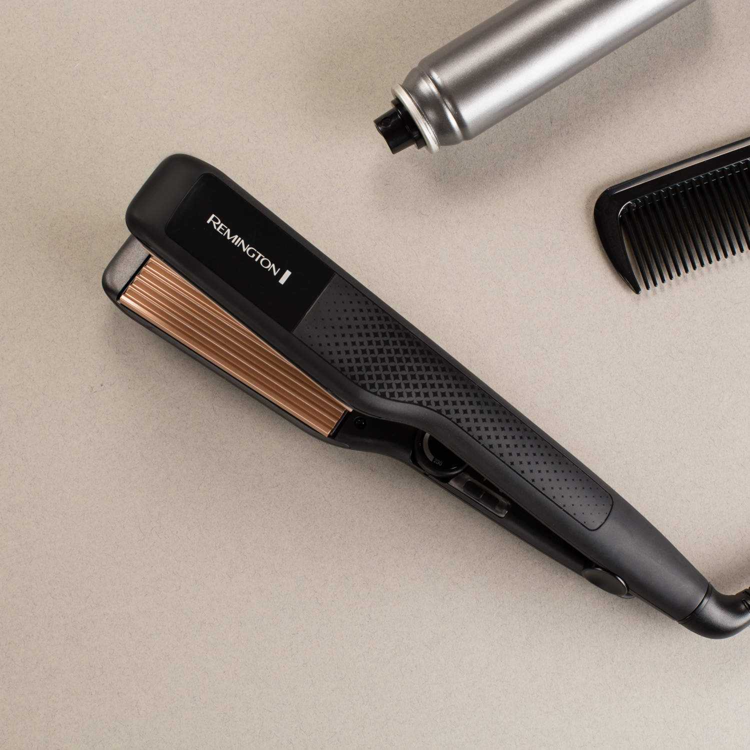 Hair straightener, hairspray, and comb on a beige surface. The straightener is black and gold.