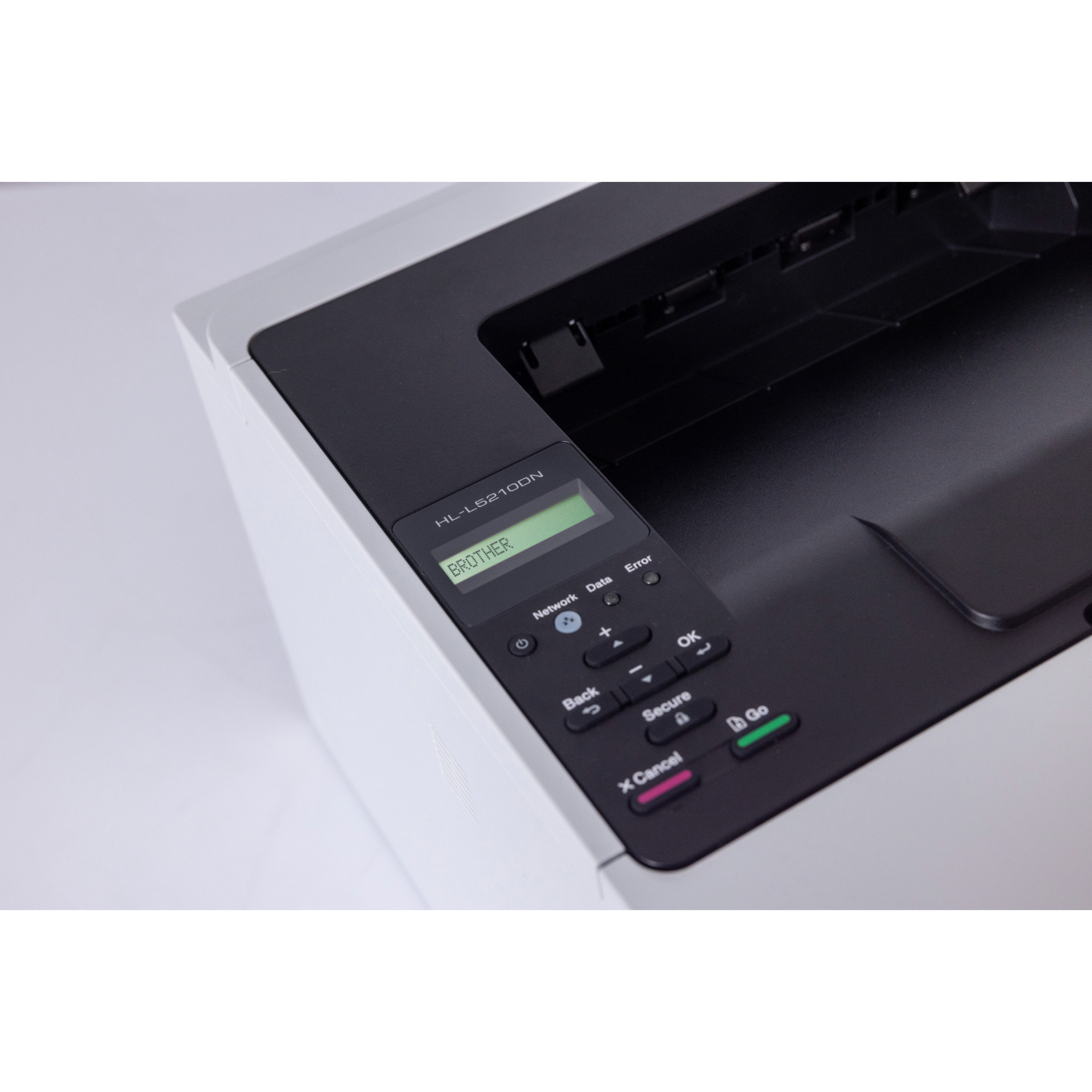 Zbliżenie czarno-białej drukarki z zielonym wyświetlaczem i przyciskami sterowania. Etykieta mówi BROTHER.