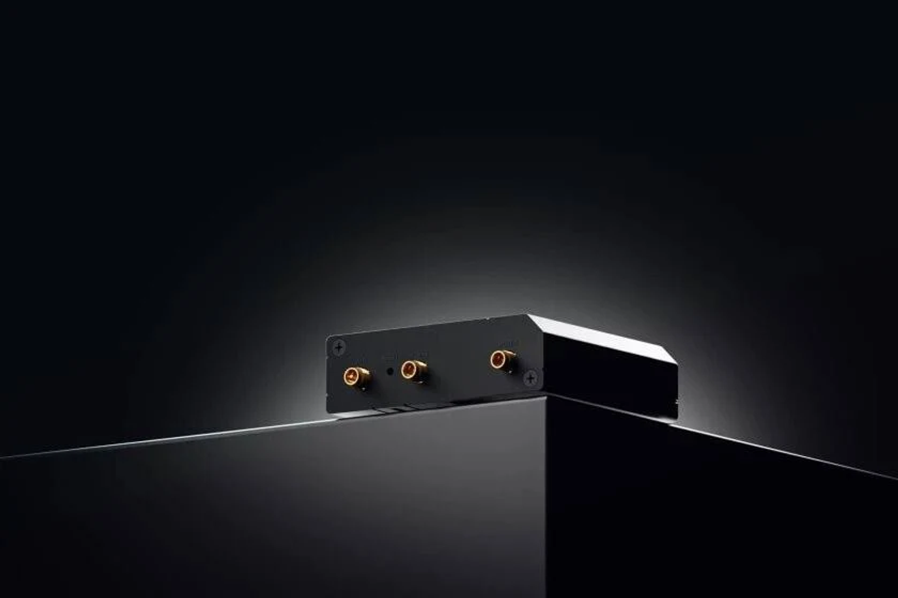 Zwart elektronisch apparaat met gouden poorten en een zwart oppervlak. Opname vanuit een hoge hoek.