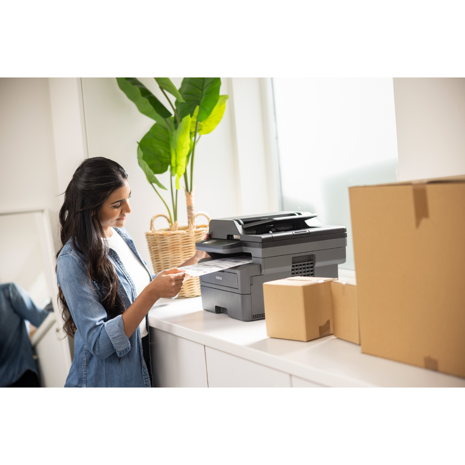 Kobieta w dżinsowej kurtce drukuje dokumenty za pomocą drukarki.