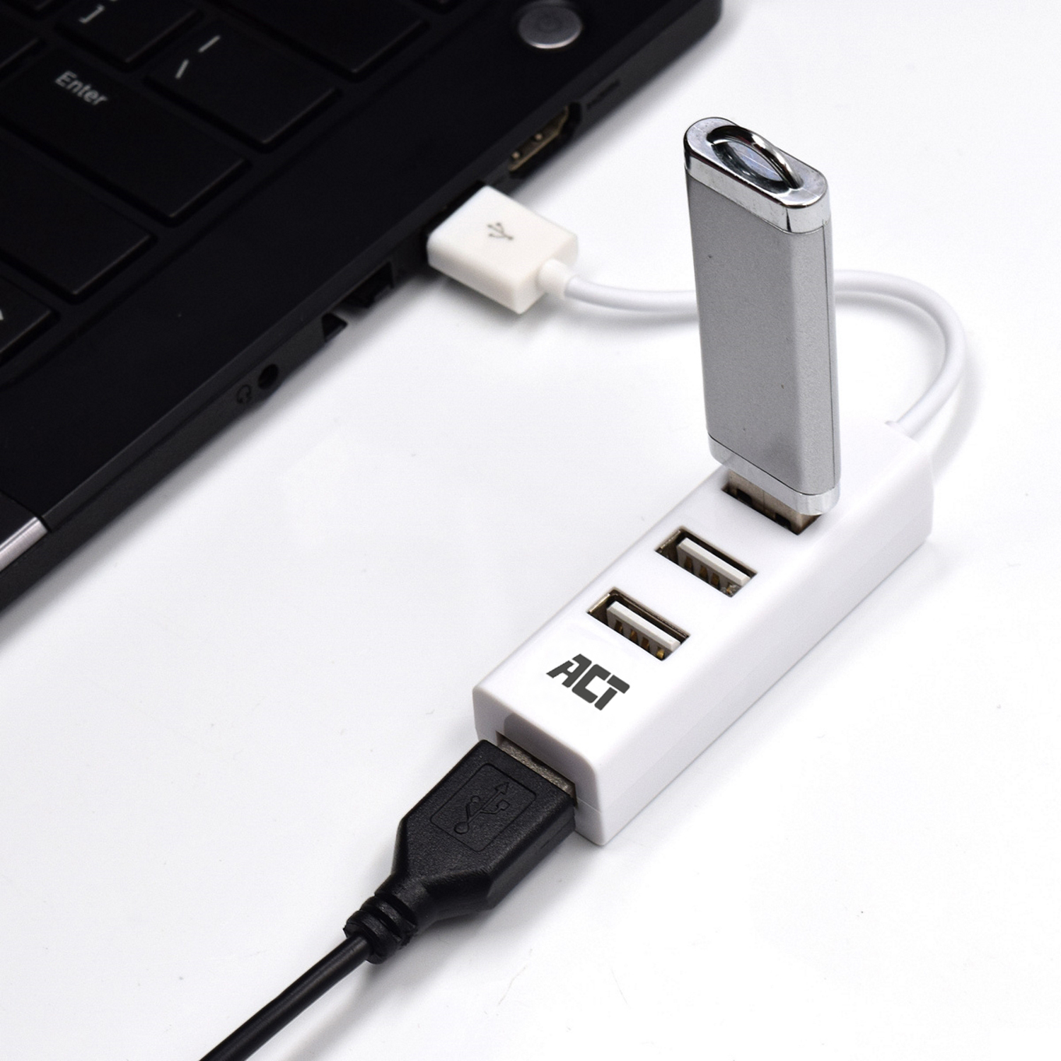 Weißer USB-Hub, an einen Laptop angeschlossen. Schwarzes USB-Kabel.