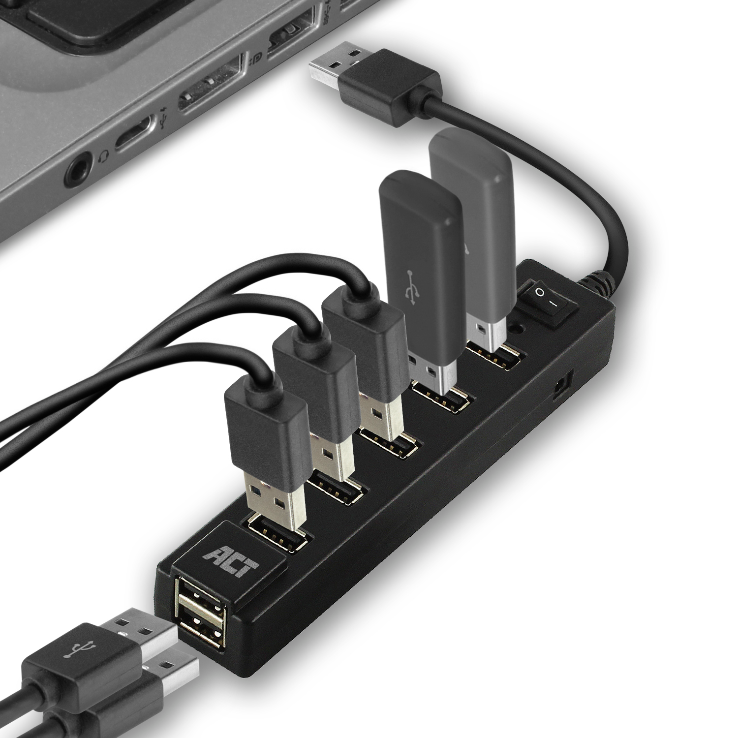 Ein schwarzer USB-Hub mit mehreren USB-Kabeln und angeschlossenen USB-Sticks, in der Nähe eines Laptops.