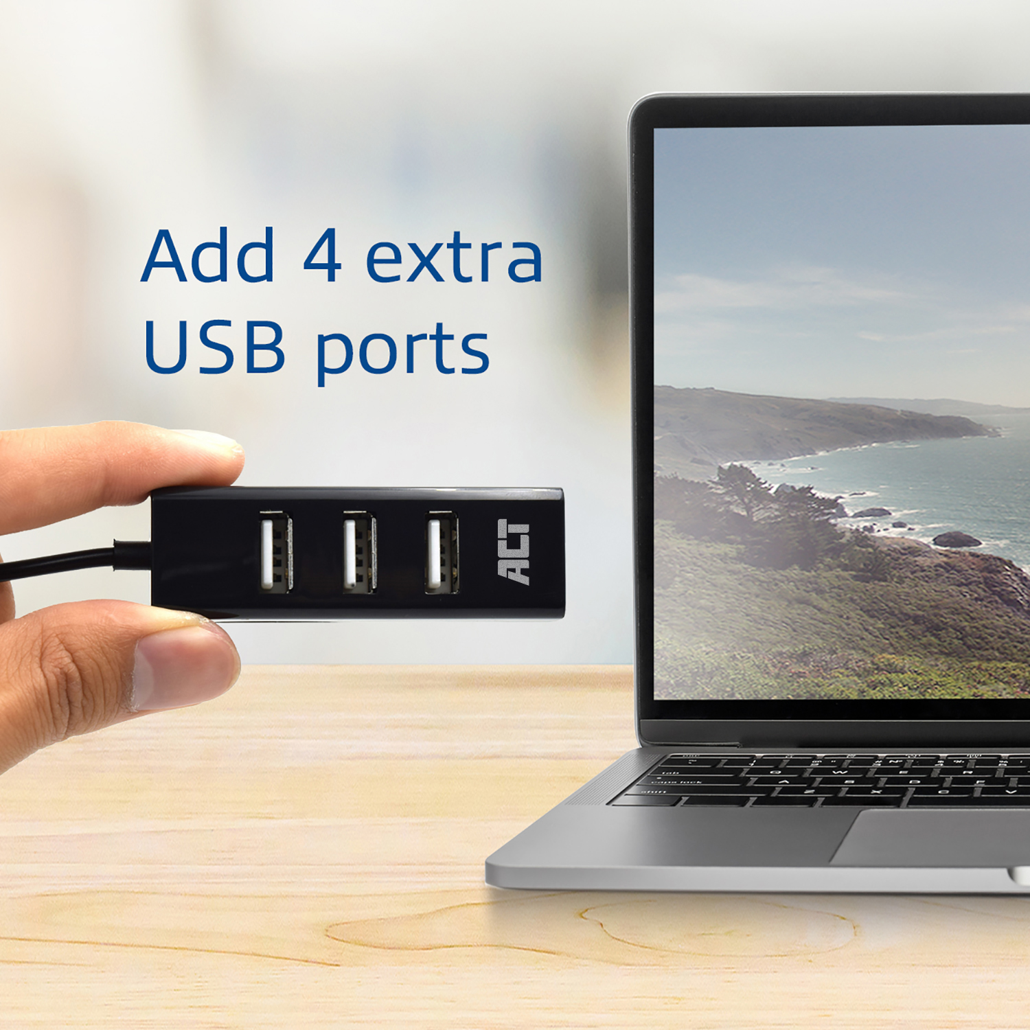 Eine Hand, die einen schwarzen USB-Hub neben einem Laptop hält und zusätzliche USB-Anschlüsse hinzufügt.