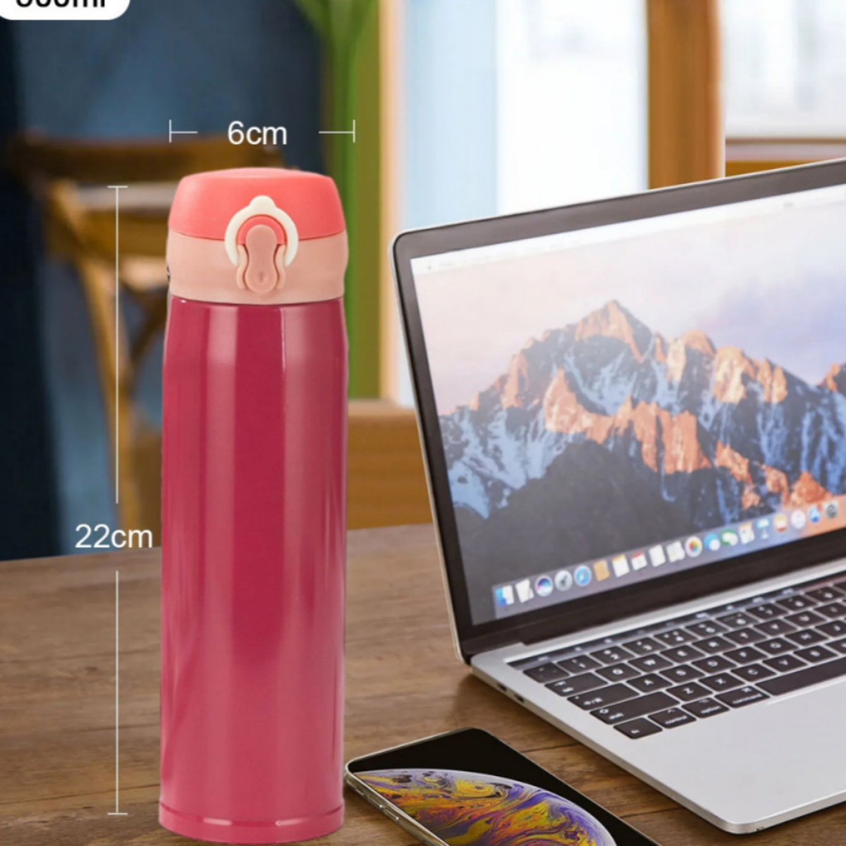 Pinke isolierte Wasserflasche mit Maßen, neben Laptop und Telefon.