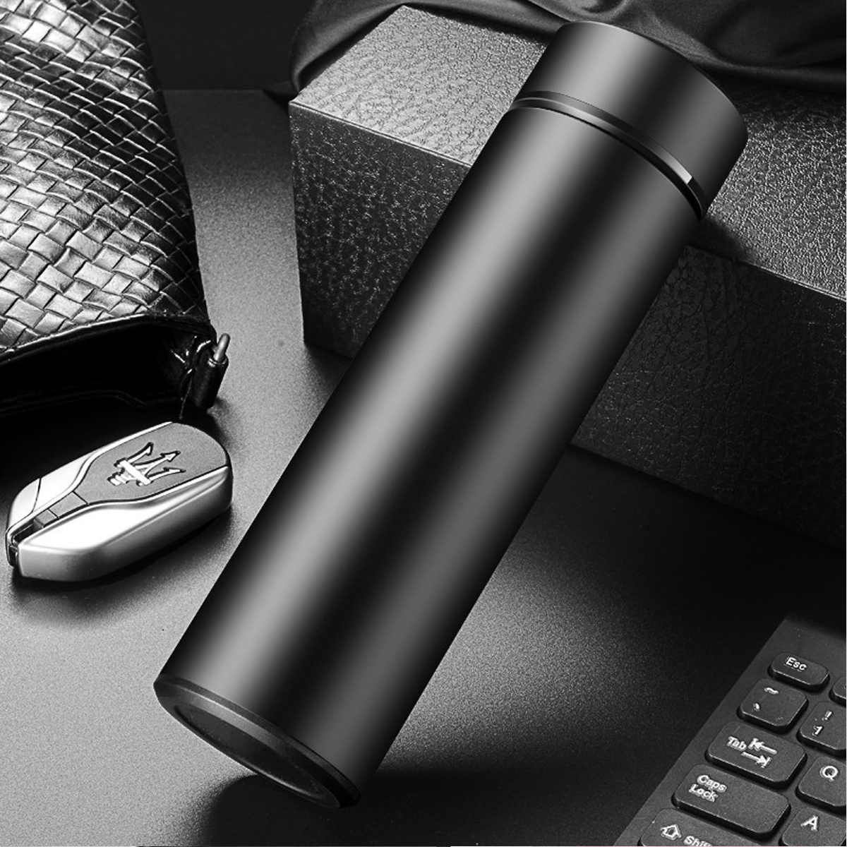 Schwarze Thermoskanne mit Autoschlüssel und Stift.
