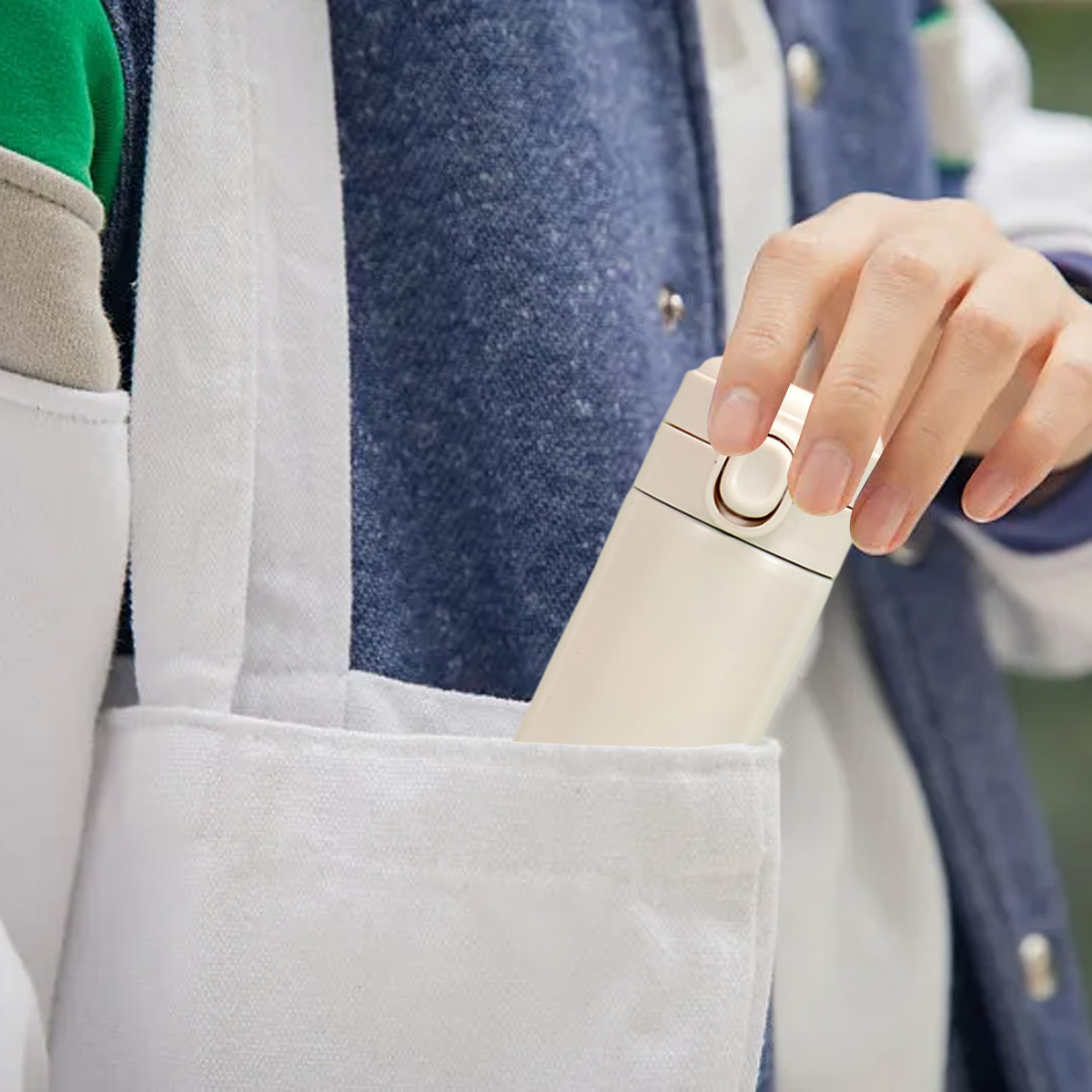 Eine Hand in einer Tasche hält einen beigen isolierten Reisebecher in einer weißen Tragetasche.