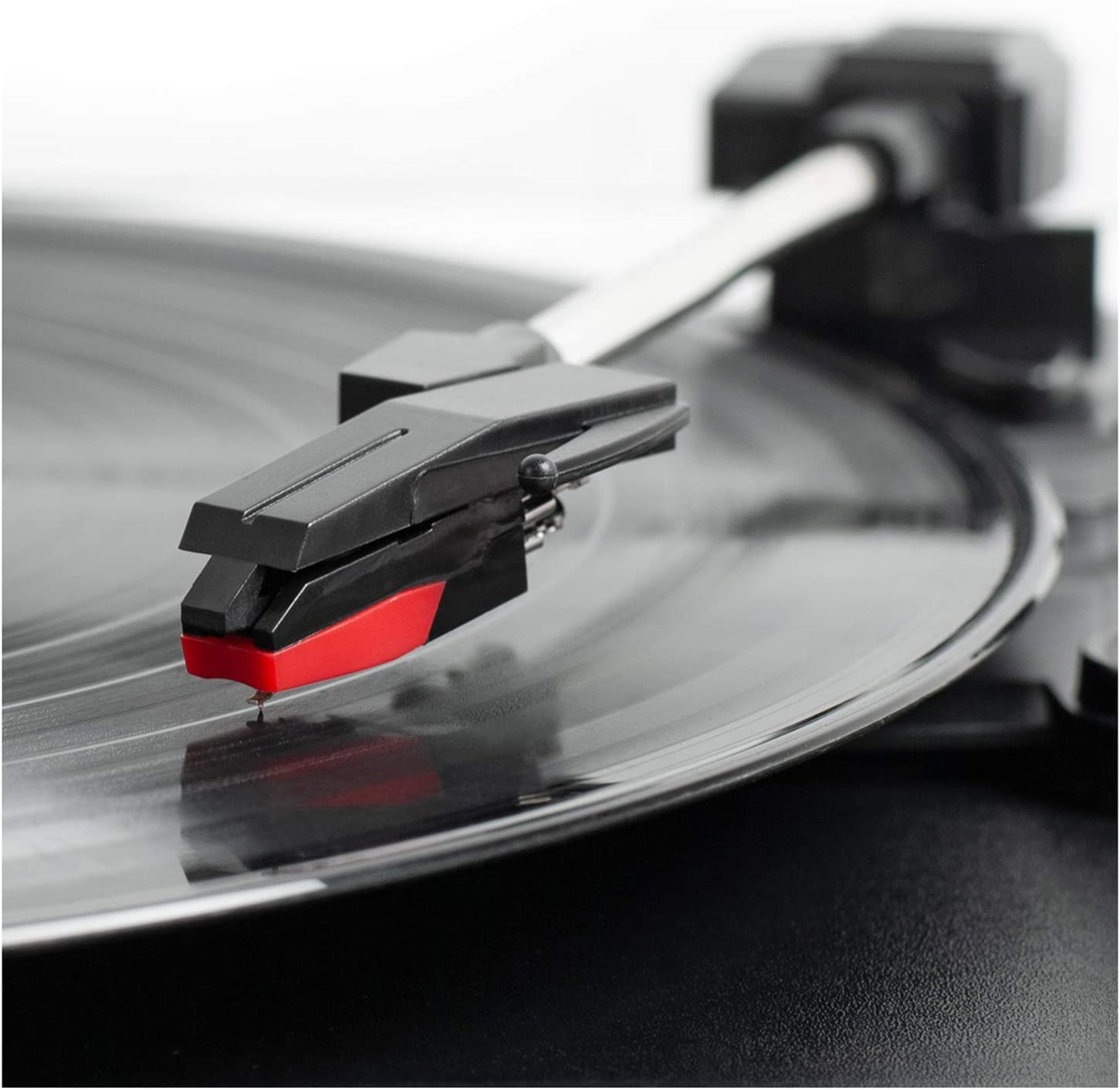 Close-up of a record player's needle on a black vinyl record. White background.