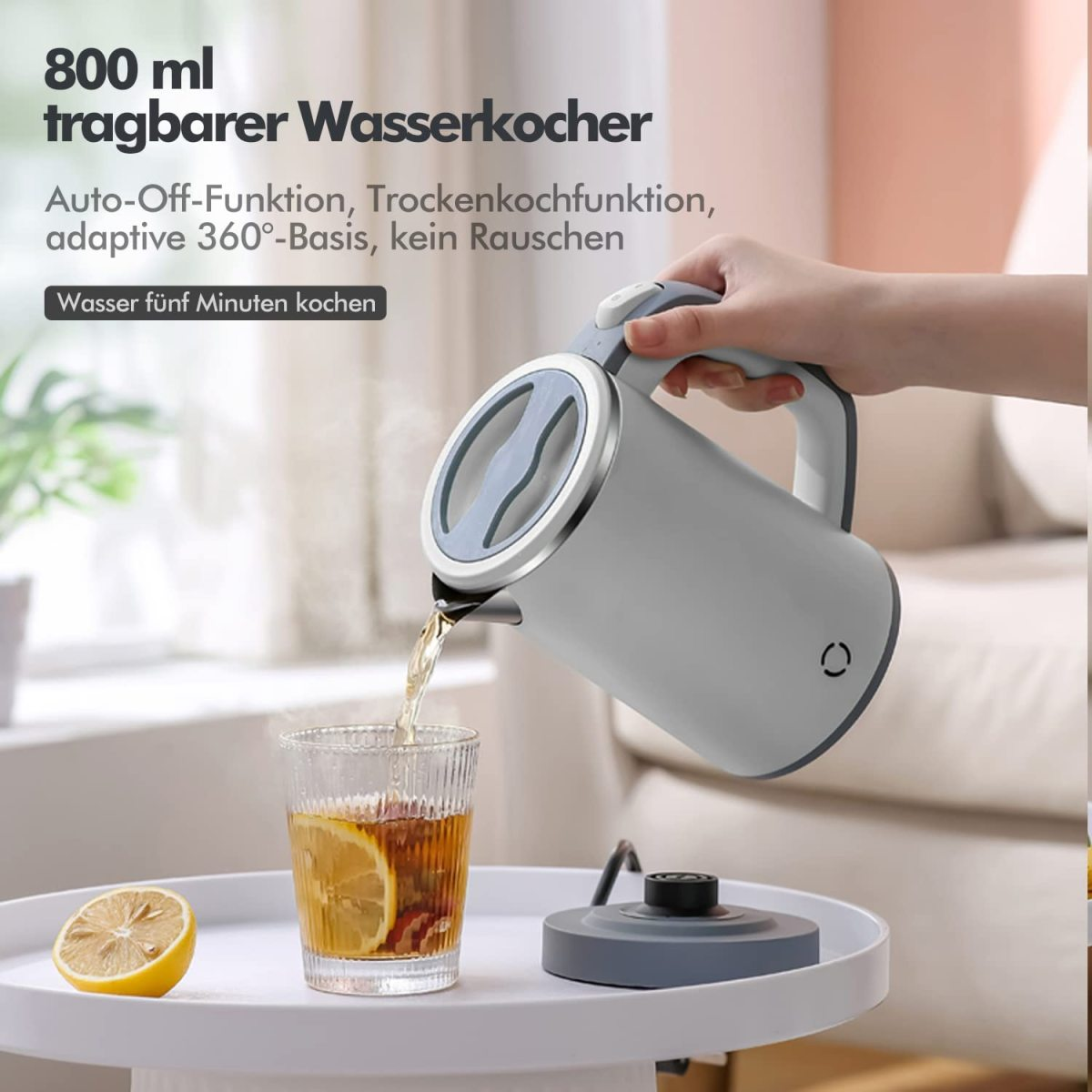 Weißer und grauer Wasserkocher gießt Wasser in ein Glas mit Zitrone und Eis.