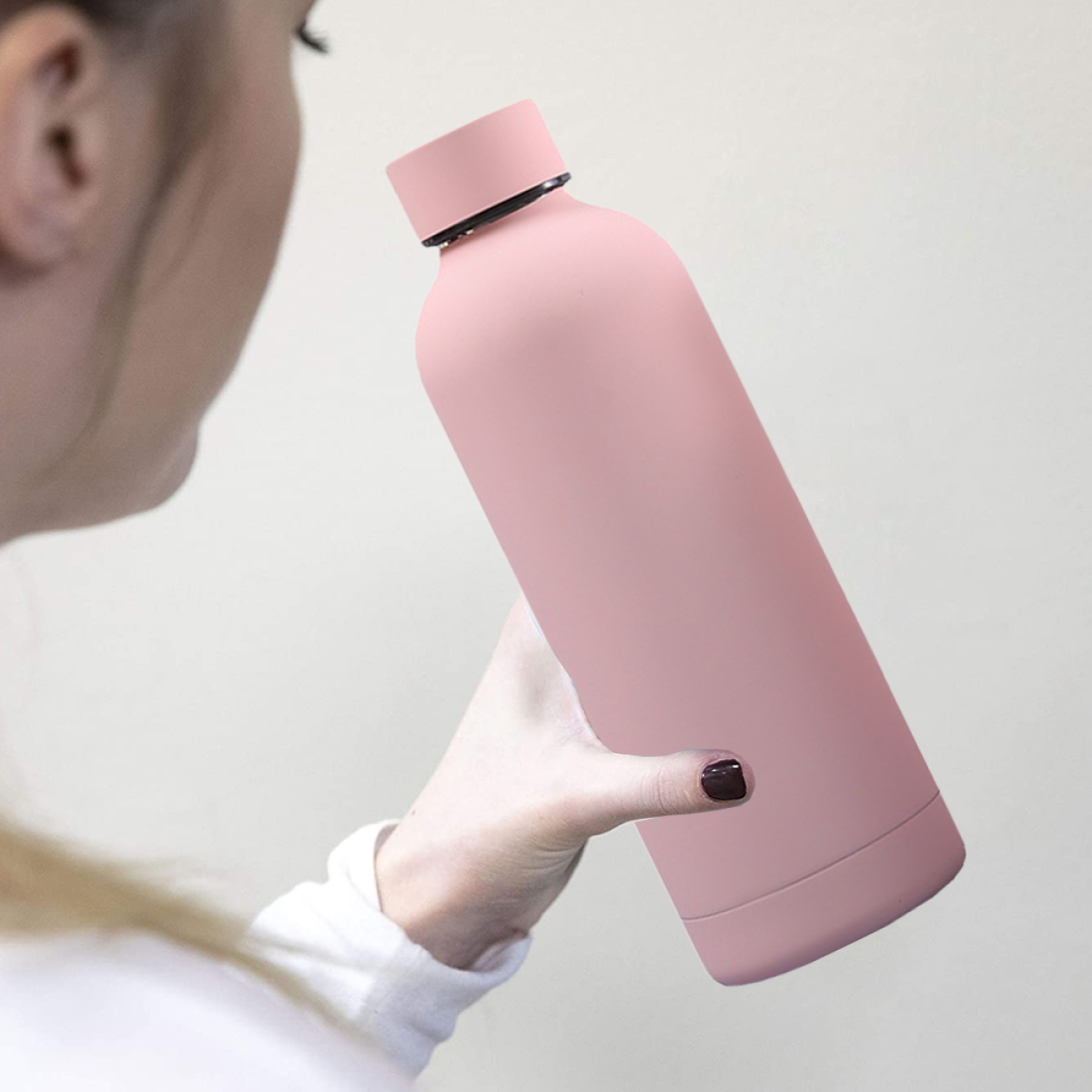 Eine Frau hält eine rosa Wasserflasche.
