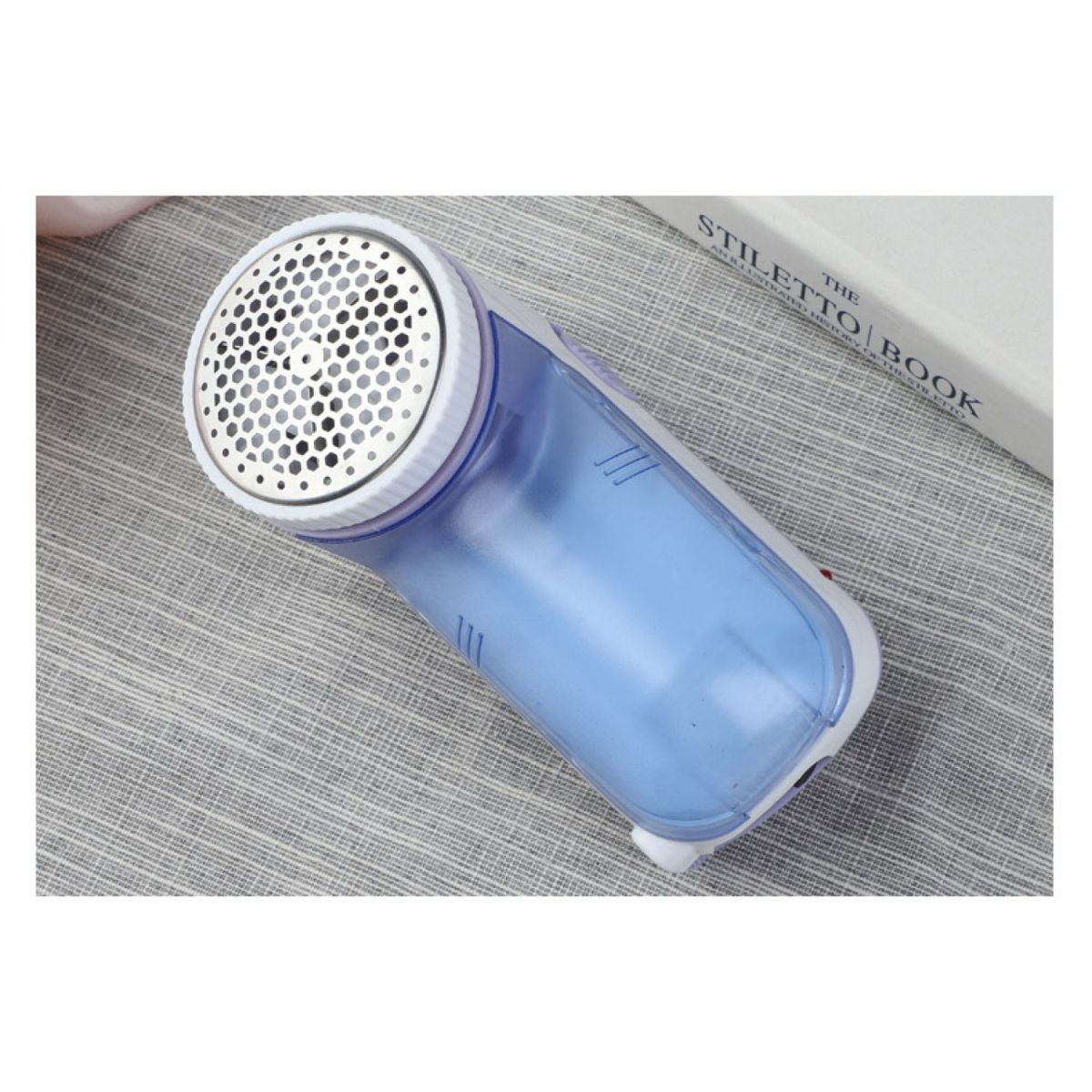 Ein Fusselentferner mit einem durchsichtigen blauen Behälter und einem weißen Oberteil.