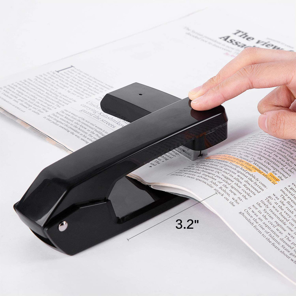 Ein Tacker auf einer Zeitungsseite. Ein Finger zeigt auf den Tacker. Die Größe beträgt 3,2".