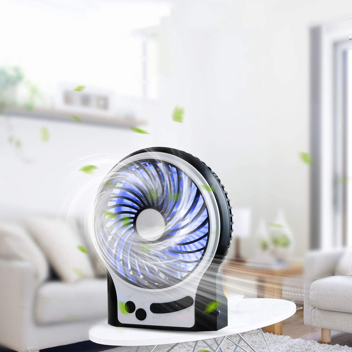 Ein tragbarer Ventilator, schwarz und weiß, mit blauen Lichtern, auf einem Tisch. Grüne Blätter in der Luft.