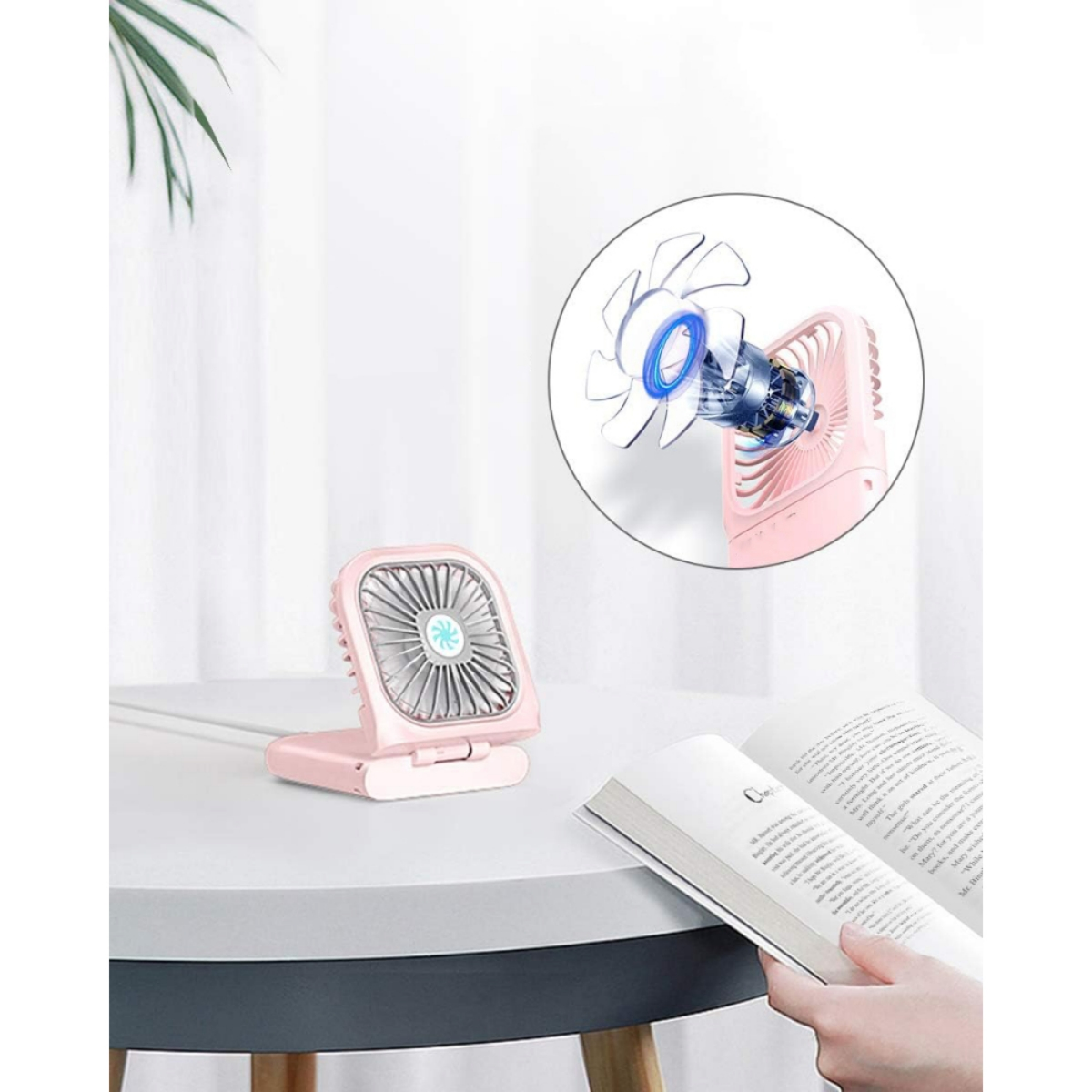 Ein pinkfarbener tragbarer Ventilator steht auf einem Tisch. Der Ventilator ist geöffnet, und ein Diagramm zeigt das Innenleben.
