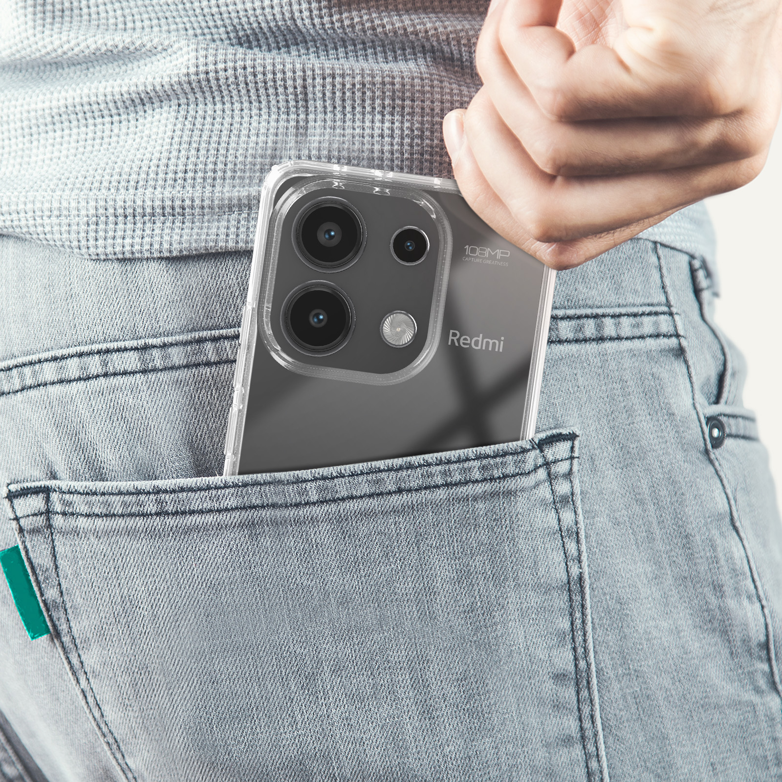 Mano di una persona con un telefono in tasca. Il telefono ha una custodia trasparente e più fotocamere.