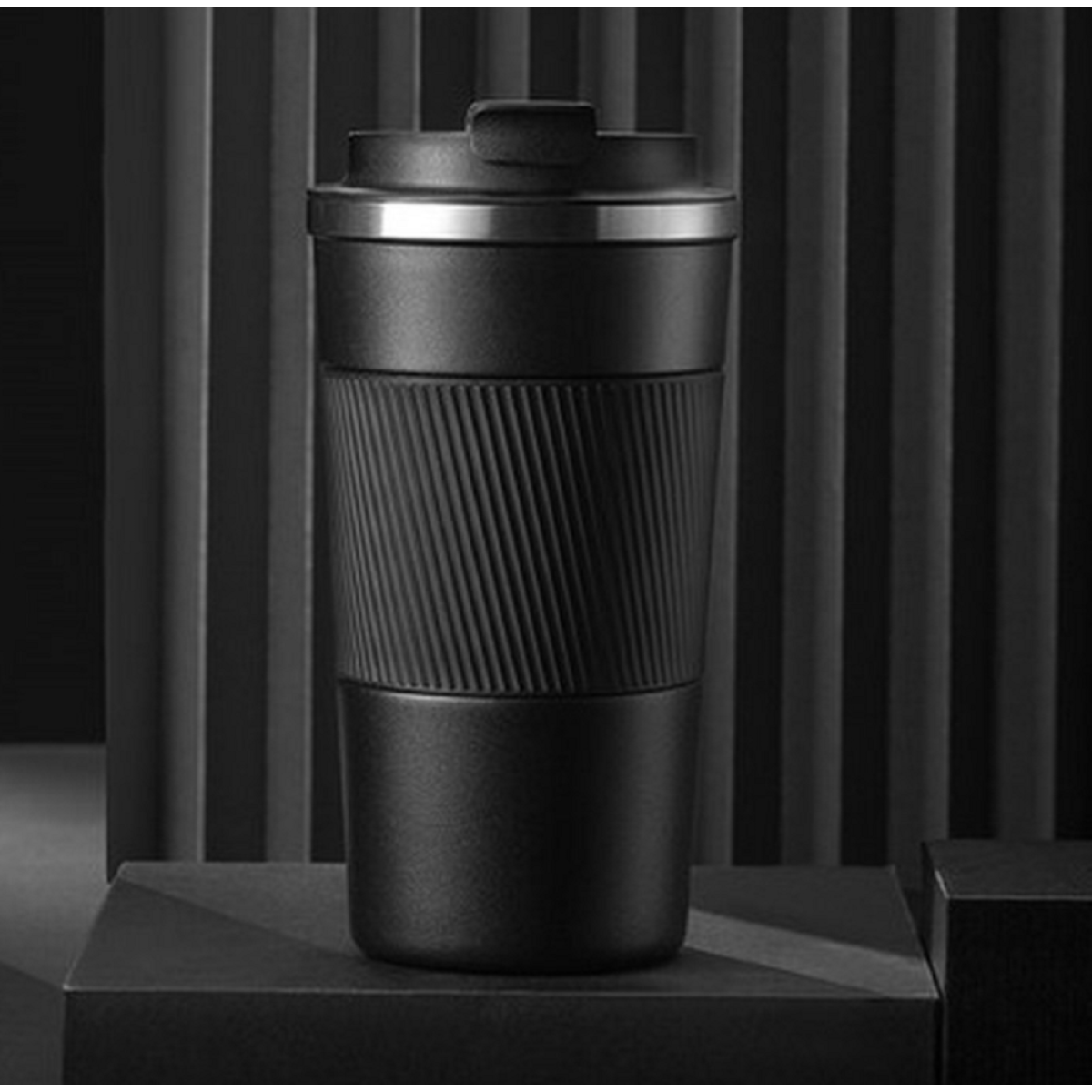 Schwarzer Reisebecher mit geripptem Griff, auf schwarzer Oberfläche. Minimalistisches Design.