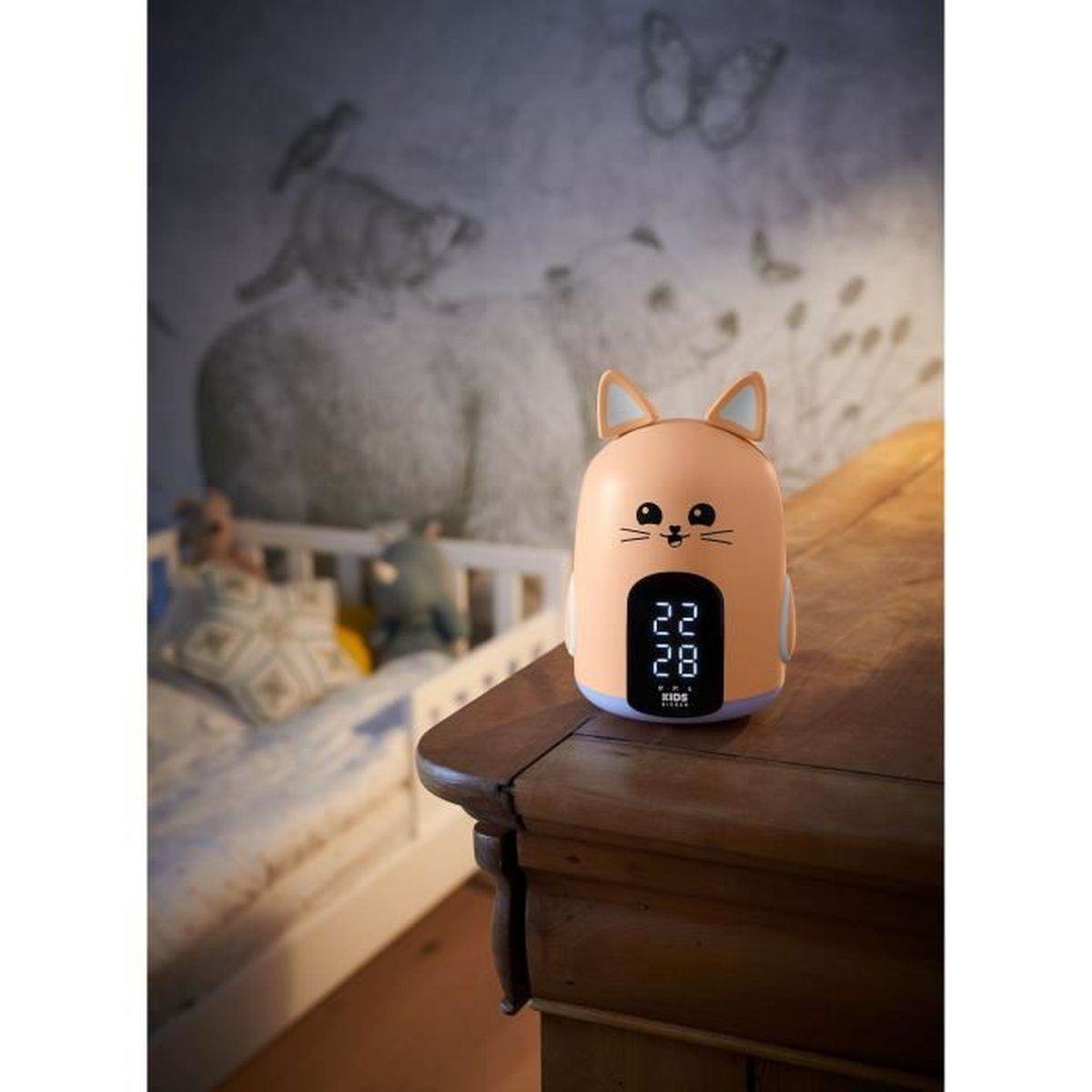 Bonito despertador naranja con forma de gato sobre una mesa de madera en un dormitorio, mostrando la hora 22:28.