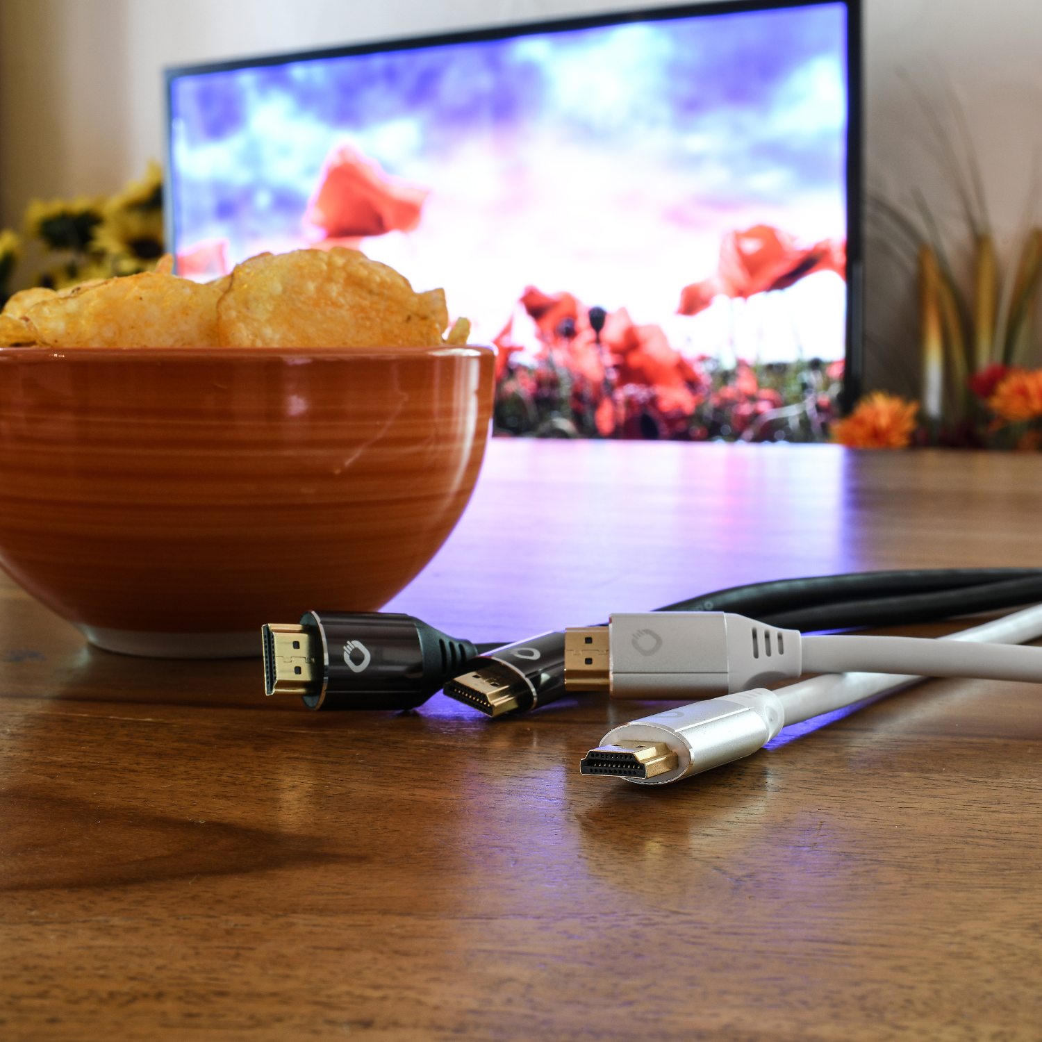 Eine Schüssel Chips, HDMI-Kabel und ein Fernseher mit verschwommenem Hintergrund.