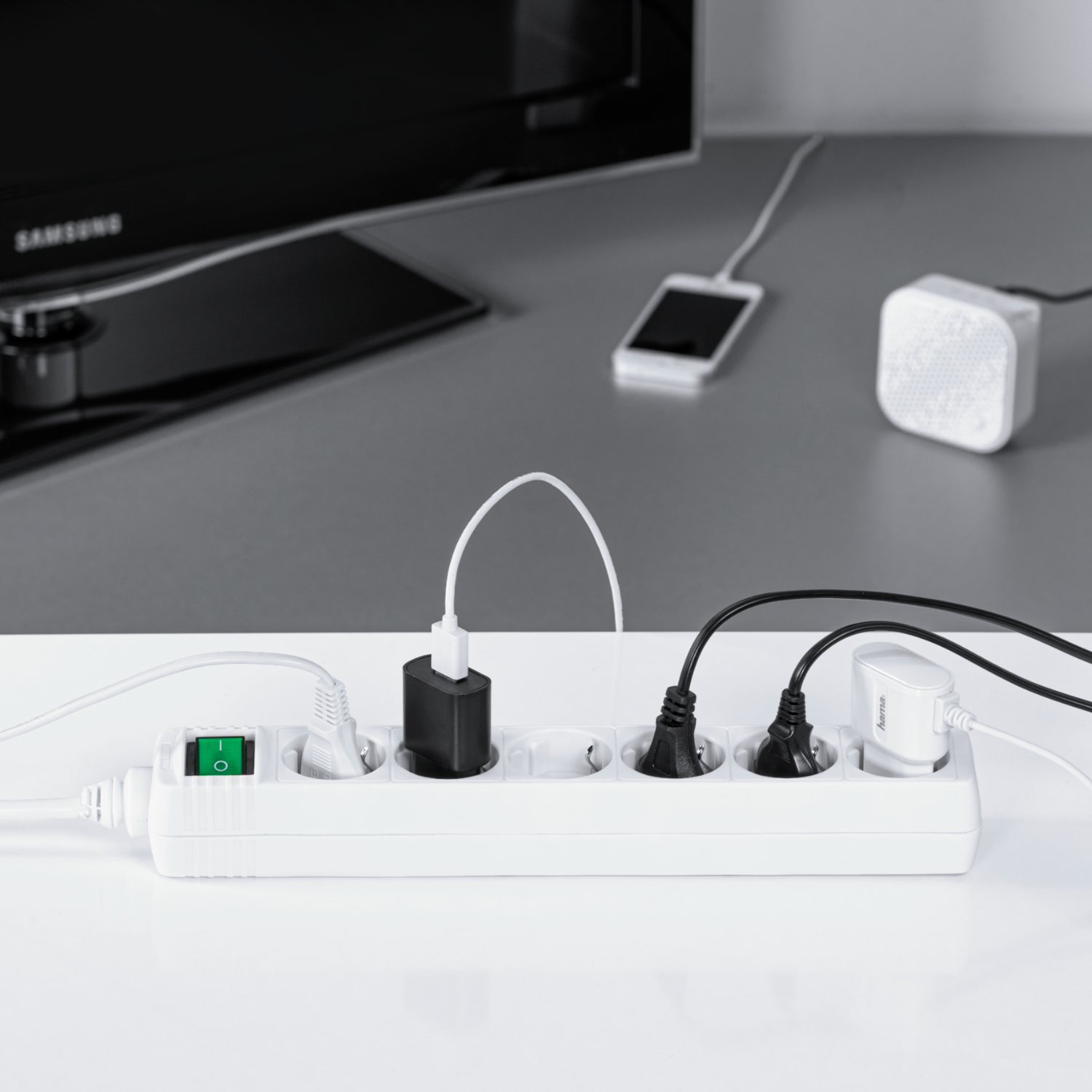 Biała listwa zasilająca z wieloma wtyczkami i zielonym włącznikiem.