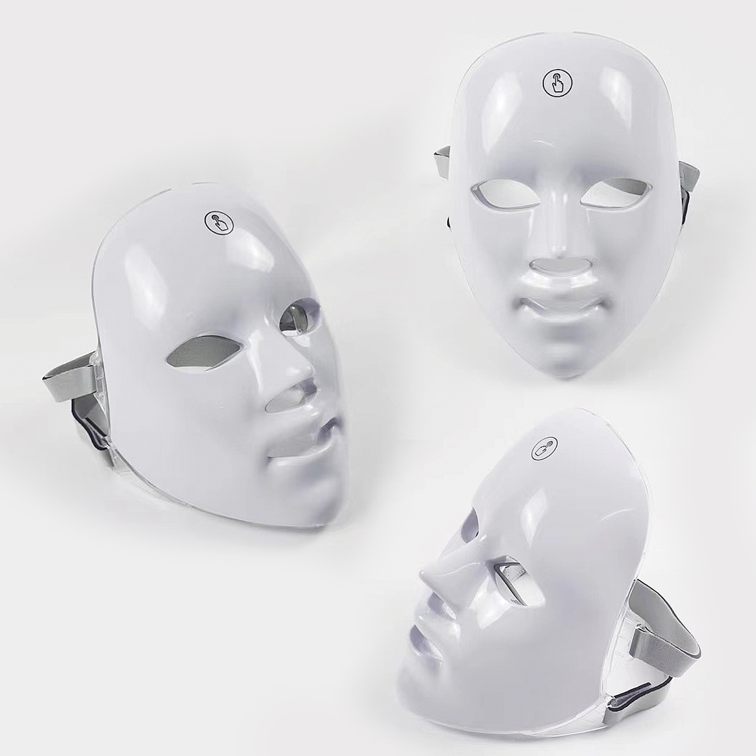 Tre maschere facciali a LED bianche. Cinghie grigie. Sfondo bianco.