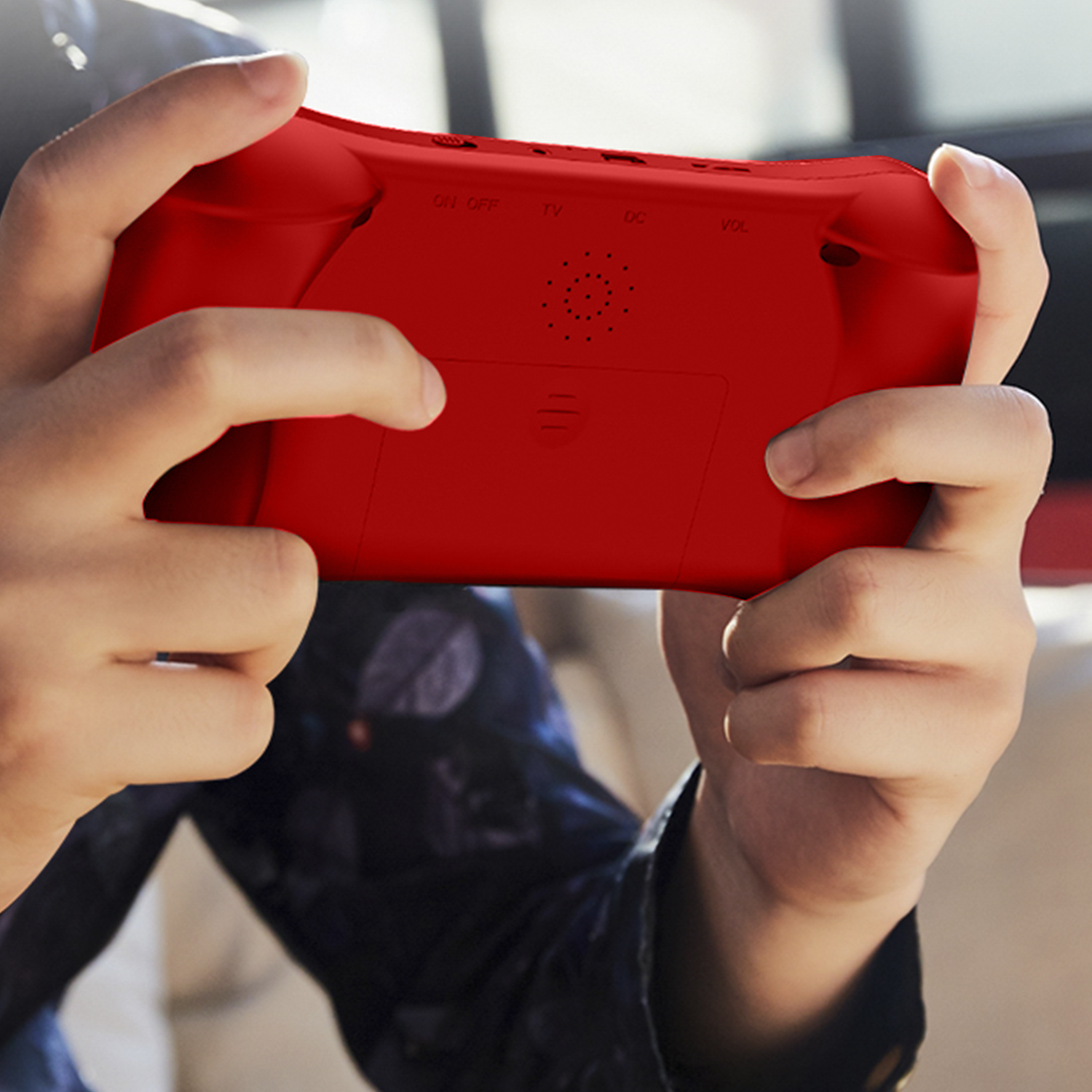 Manos sosteniendo una consola de juegos portátil roja. Se ve la parte trasera.