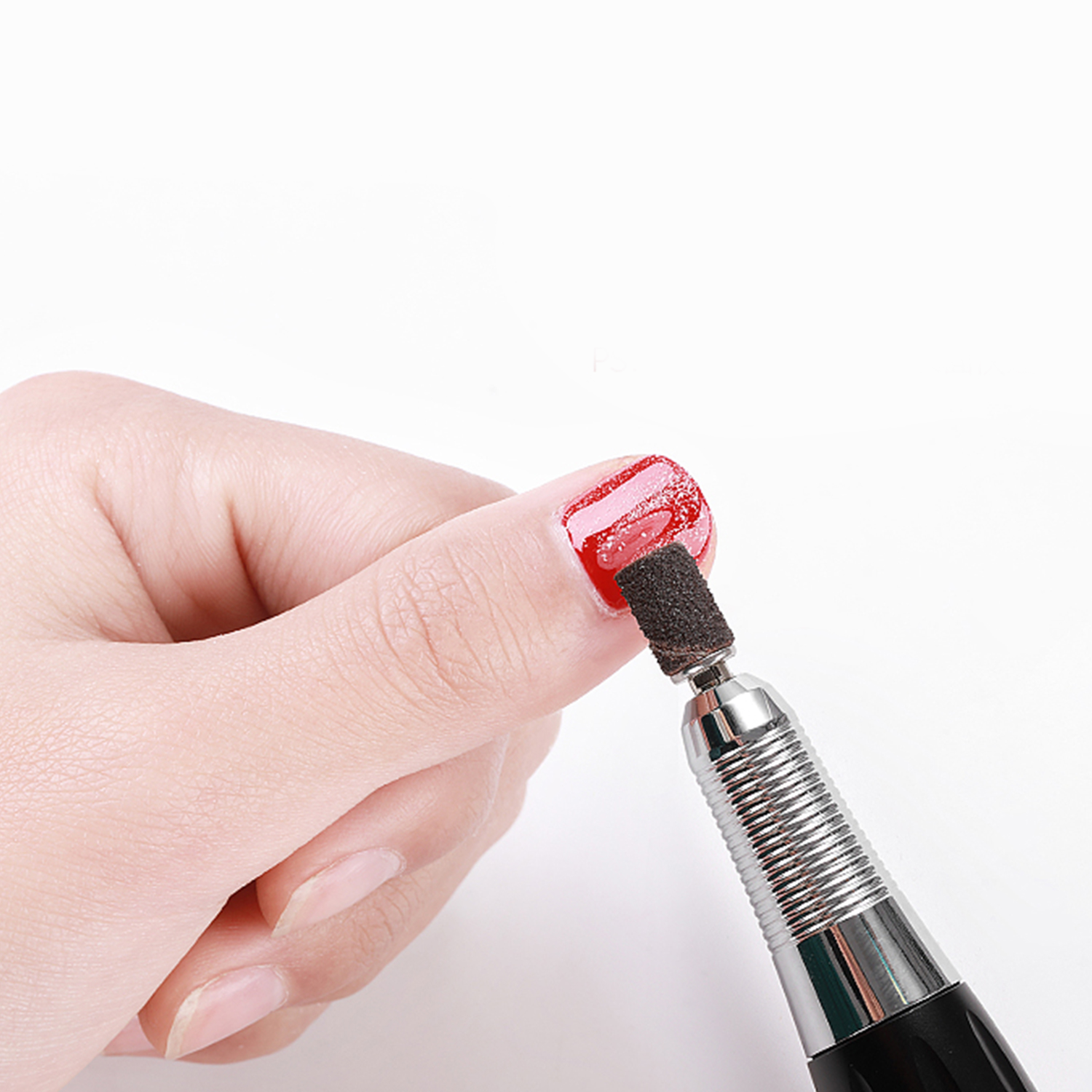 Manicure con un'unghia dipinta di rosso e un trapano per unghie su sfondo bianco.
