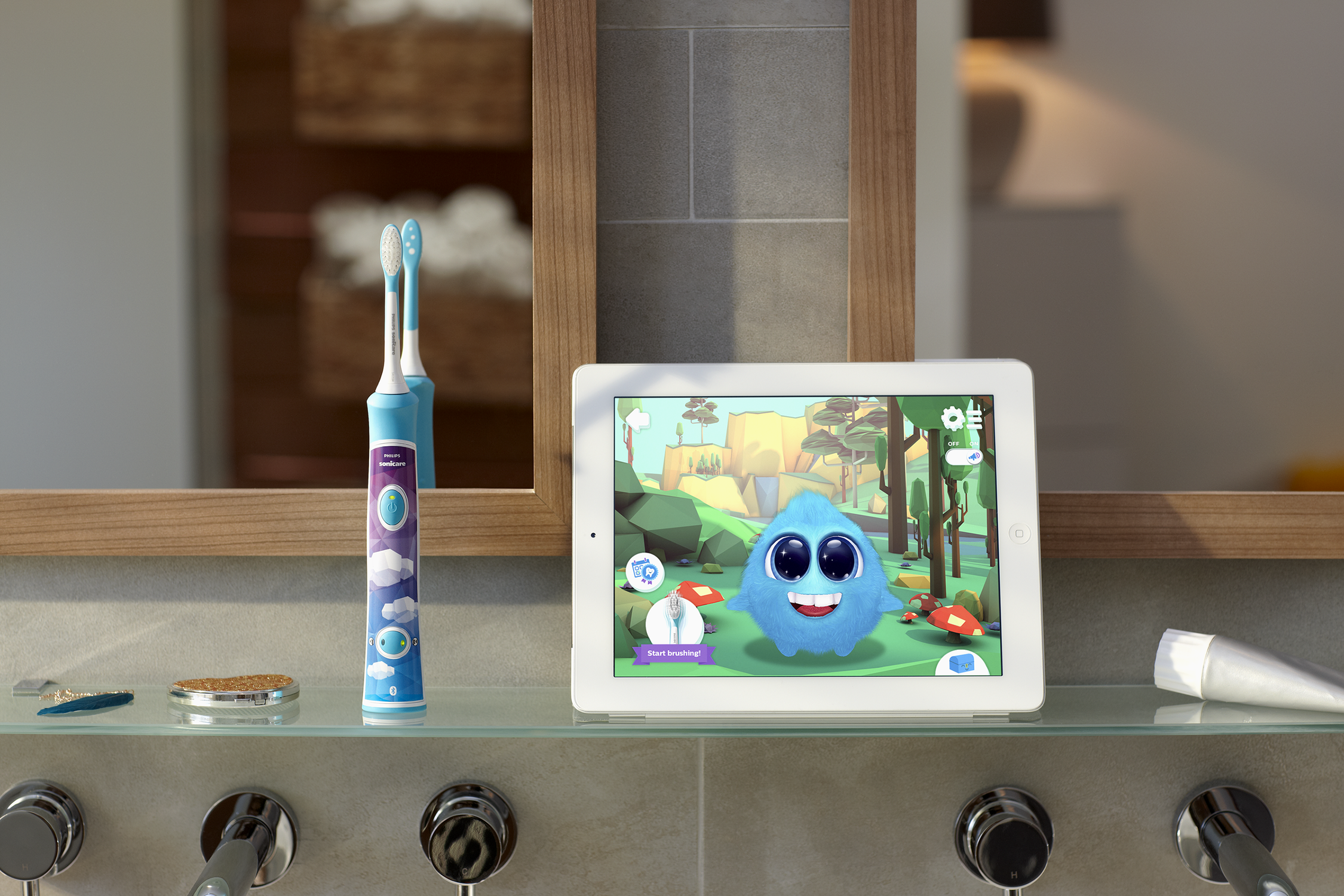 Badkamer met tandenborstel en tablet met cartoon. Spiegeltje erboven, wastafel eronder.