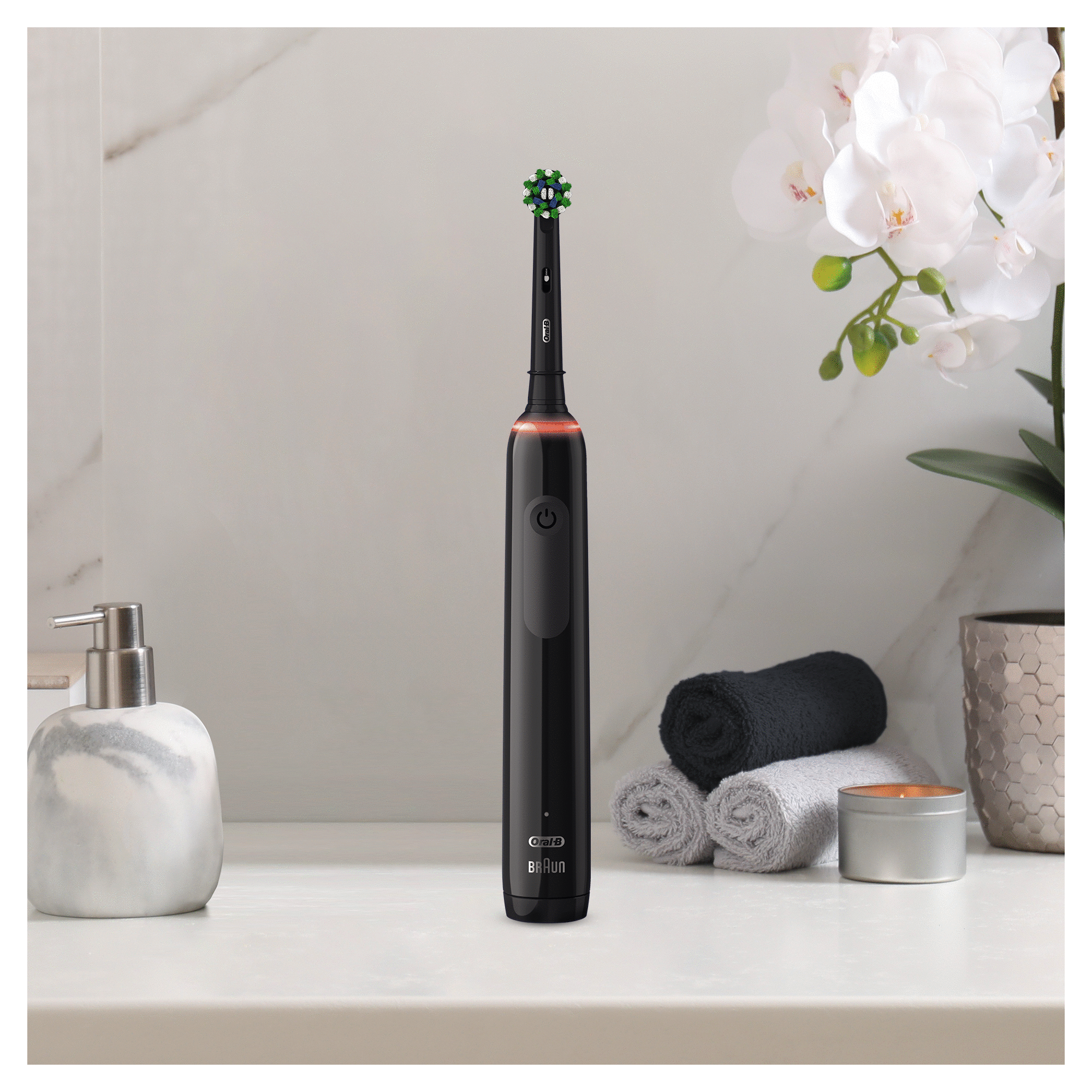 Cepillo de dientes eléctrico negro sobre superficie blanca, ambiente de baño con toallas.