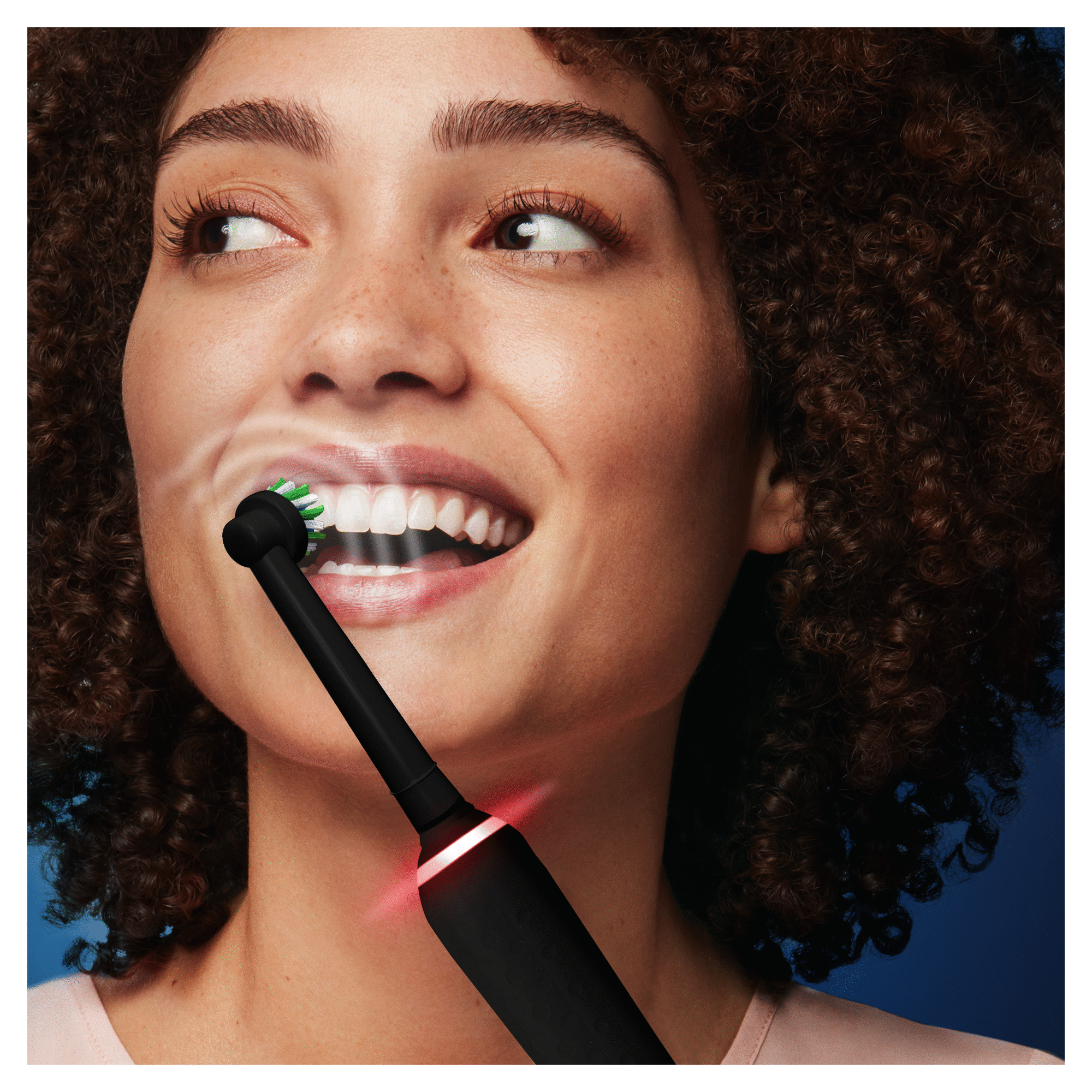 Mujer cepillándose los dientes con un cepillo eléctrico negro. Enfoque en su boca abierta y dientes.
