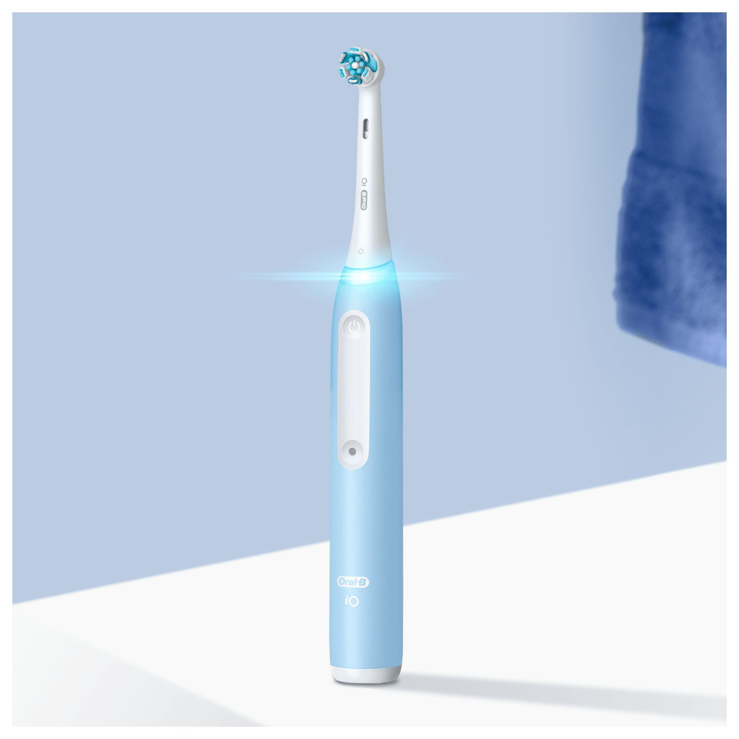 Niebieska i biała elektryczna szczoteczka do zębów. Główka biała z niebieskim włosiem. Logo Oral B.