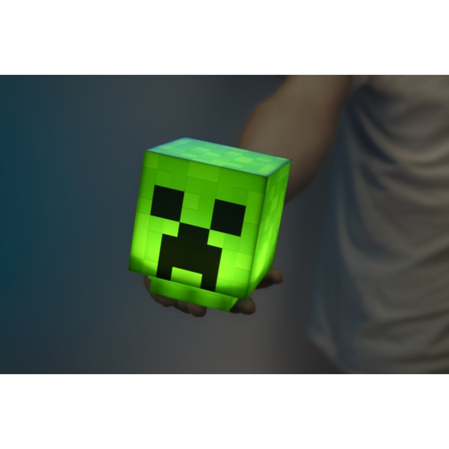 Zielona lampa Minecraft Creeper trzymana w dłoni na ciemnym tle.