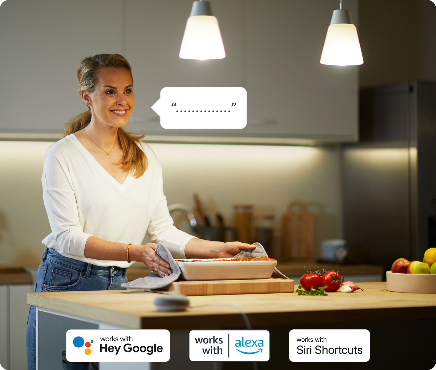 Kobieta w kuchni trzymająca naczynie do pieczenia, rozmawiająca z urządzeniem smart home. Loga asystentów głosowych.