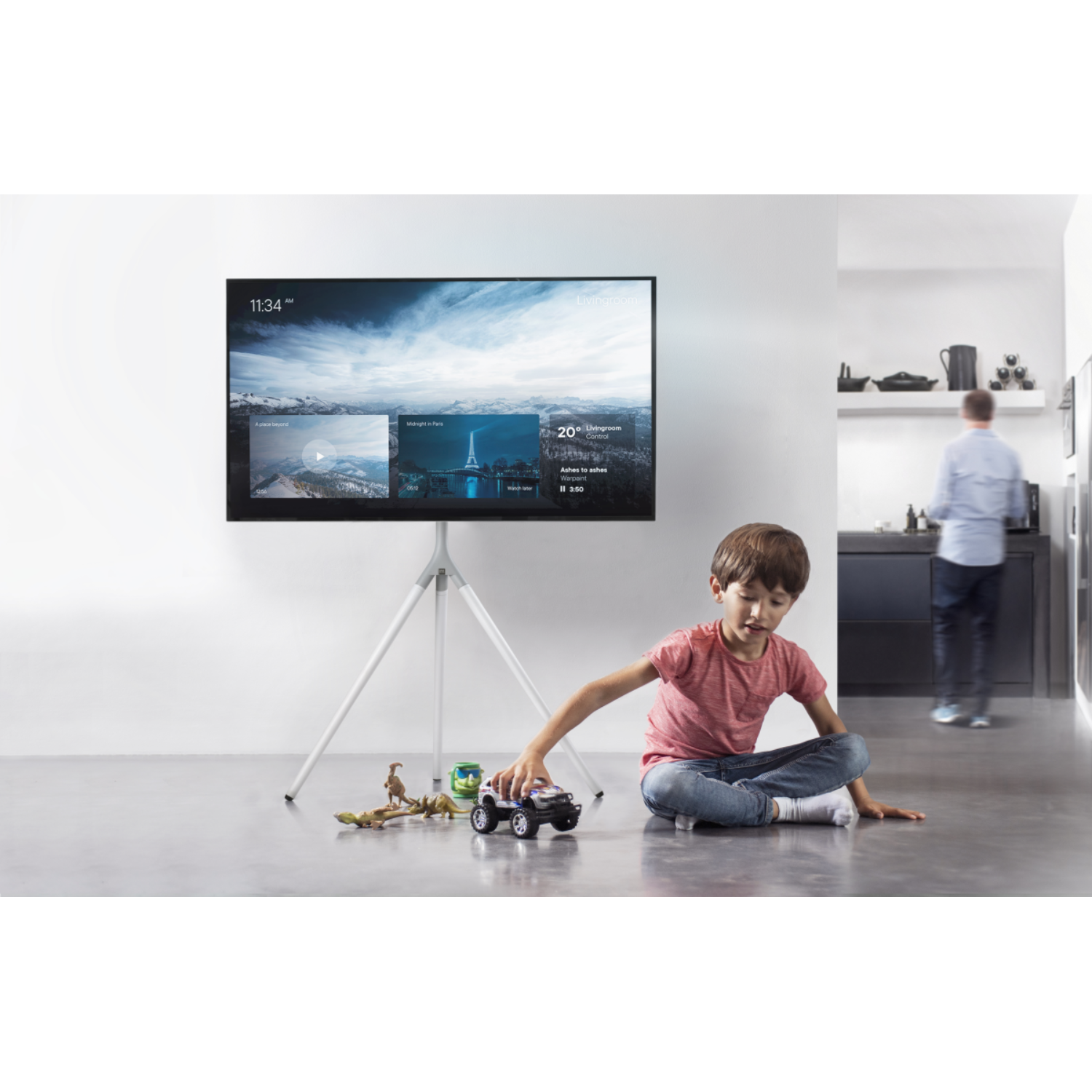 Een kind speelt met speelgoed voor een grote tv op een statief.