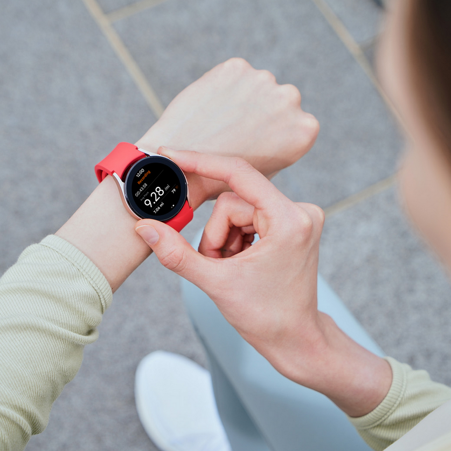 Eine Person, die eine rote Smartwatch am Handgelenk trägt. Die Uhr zeigt Zeit, Schritte und Herzfrequenz an.