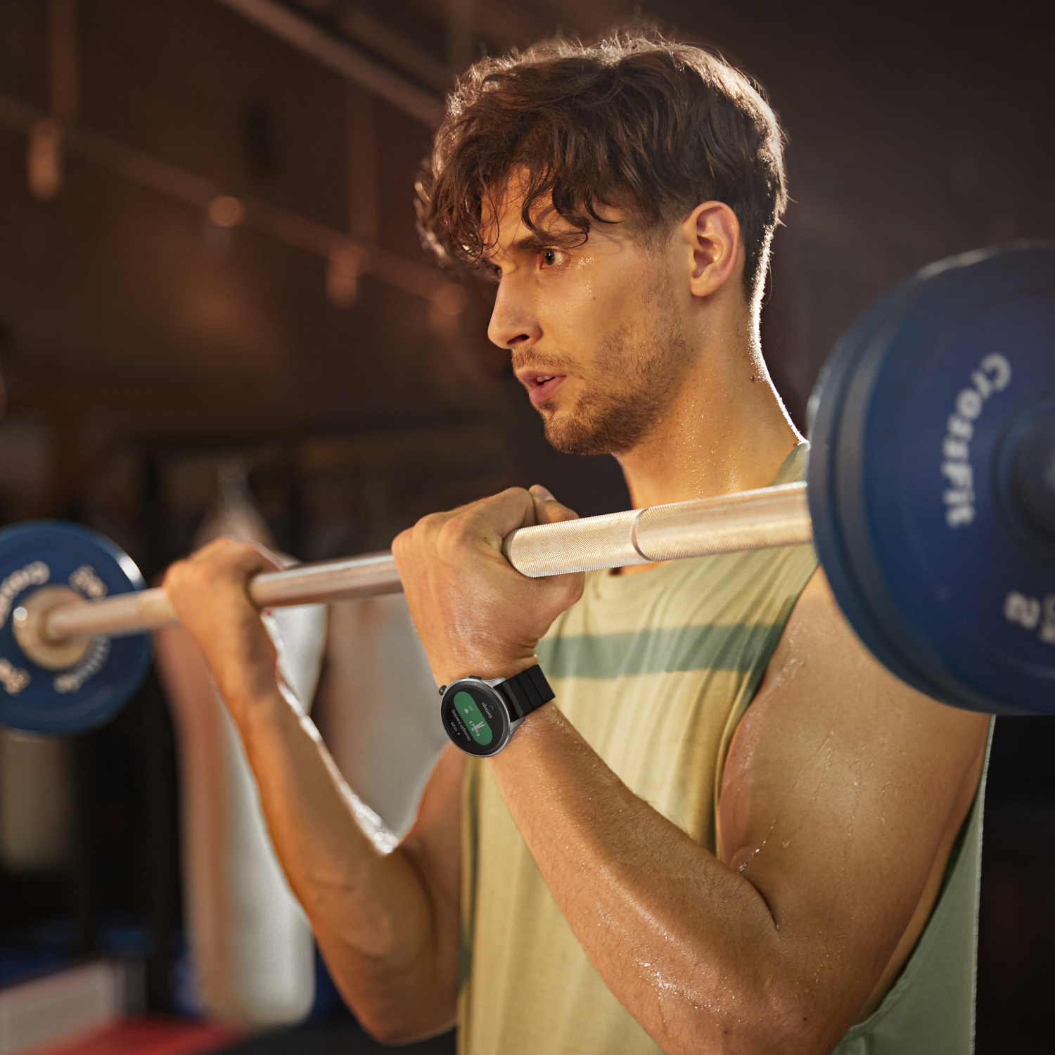 Ein Mann im Fitnessstudio, der Gewichte hebt und eine Smartwatch trägt. Er ist konzentriert.