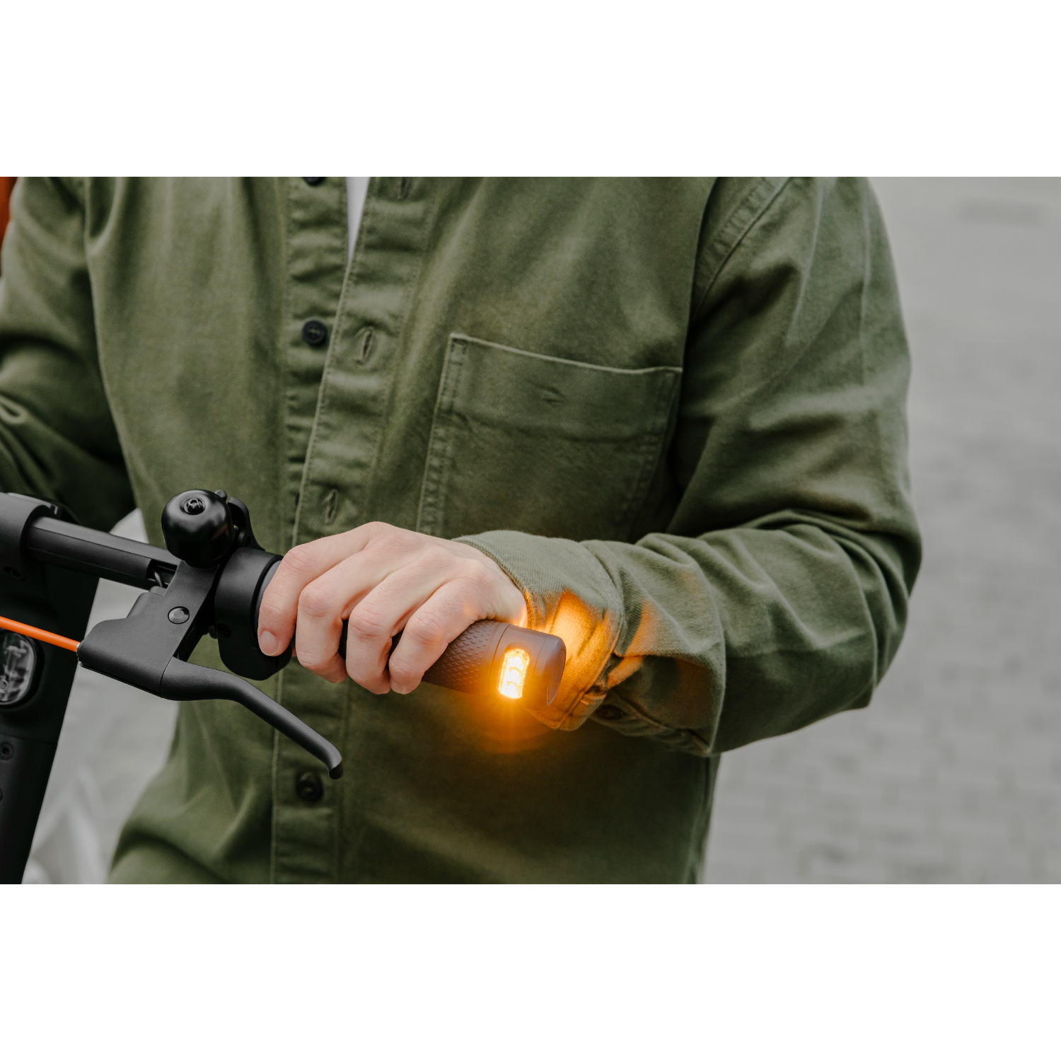 Una persona tiene il manubrio di uno scooter. Il manubrio ha una luce arancione all'estremità.